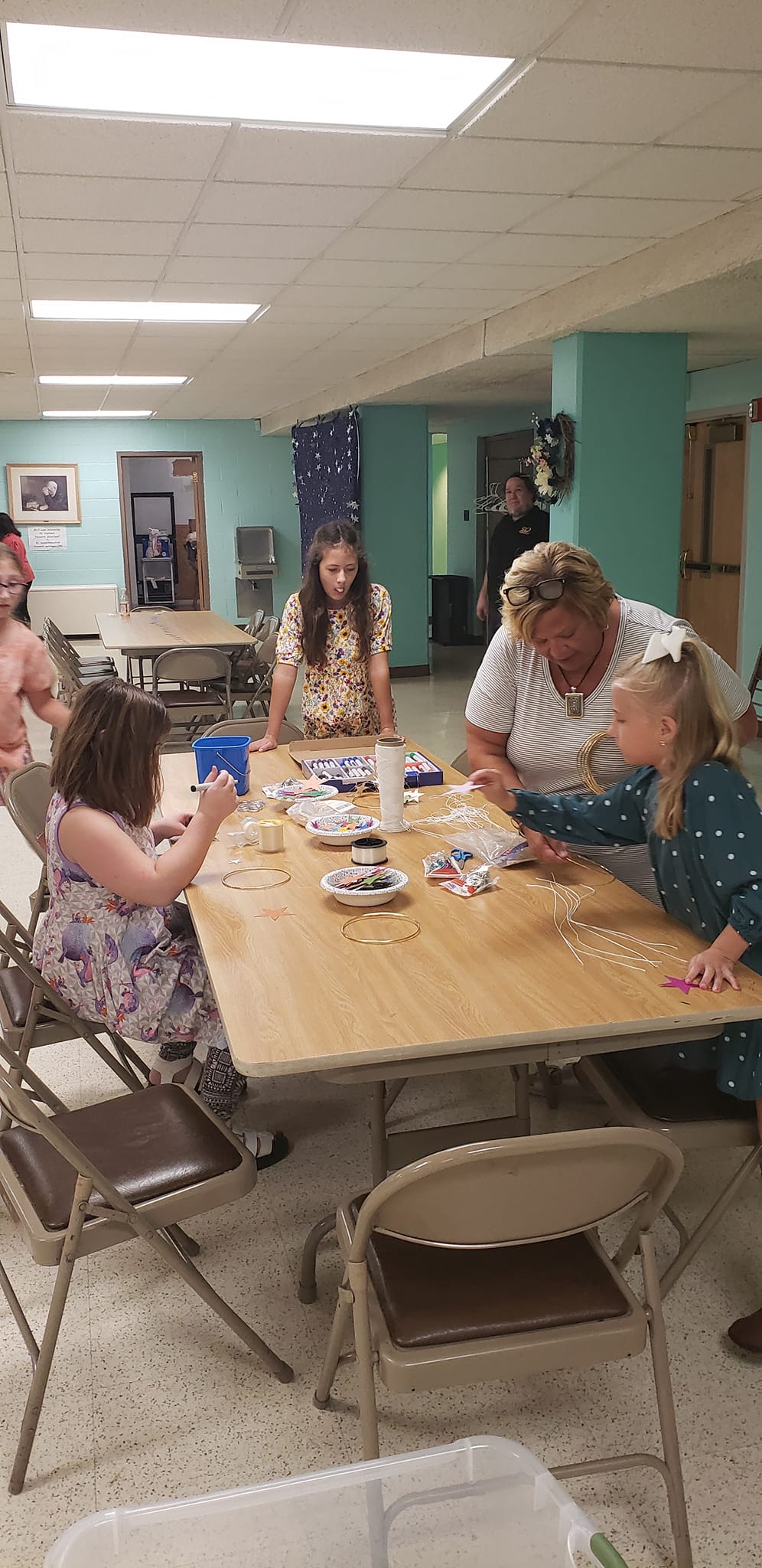 People seated around a table in a community room, playing a card game with snacks and papers.