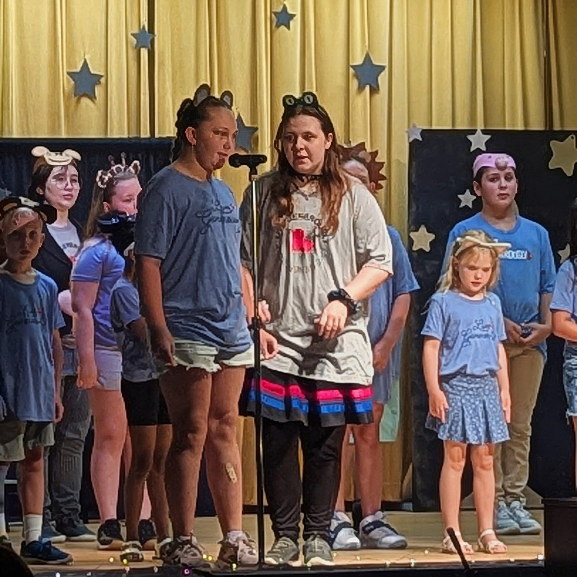 Children and teens on a stage with star decorations, preparing for a performance