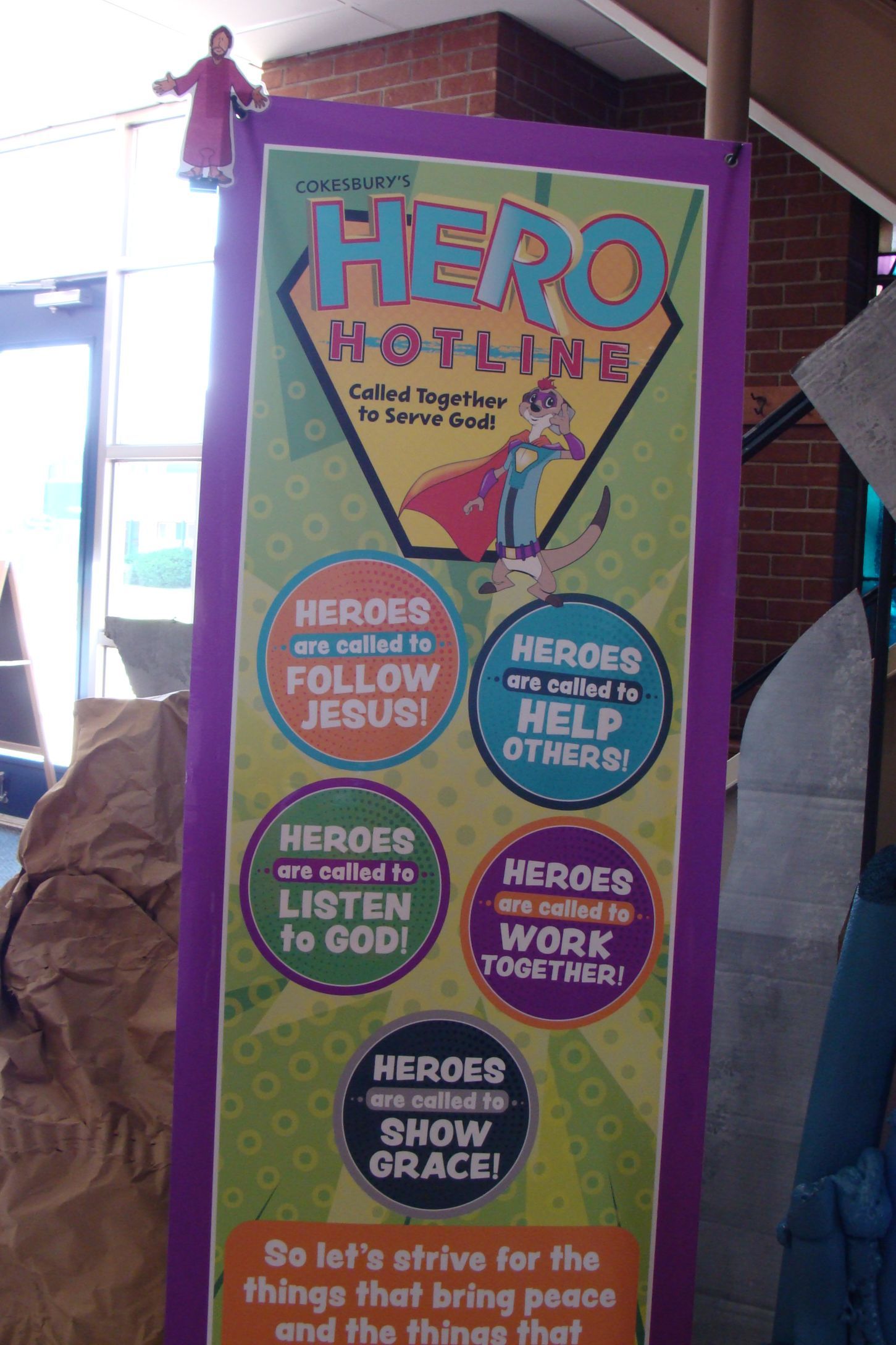 Colorful “Hero Houting” poster with circles listing ways to help, on a purple display board.