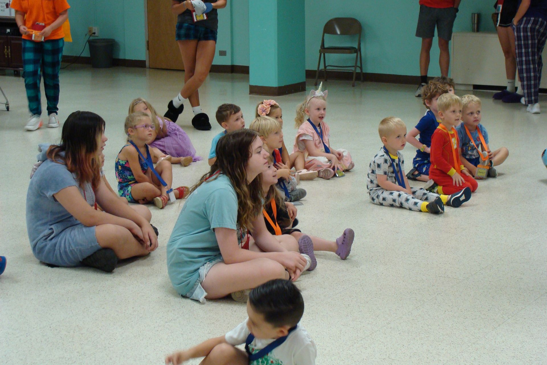Children sitting on the floor in a classroom, listening during a group activity