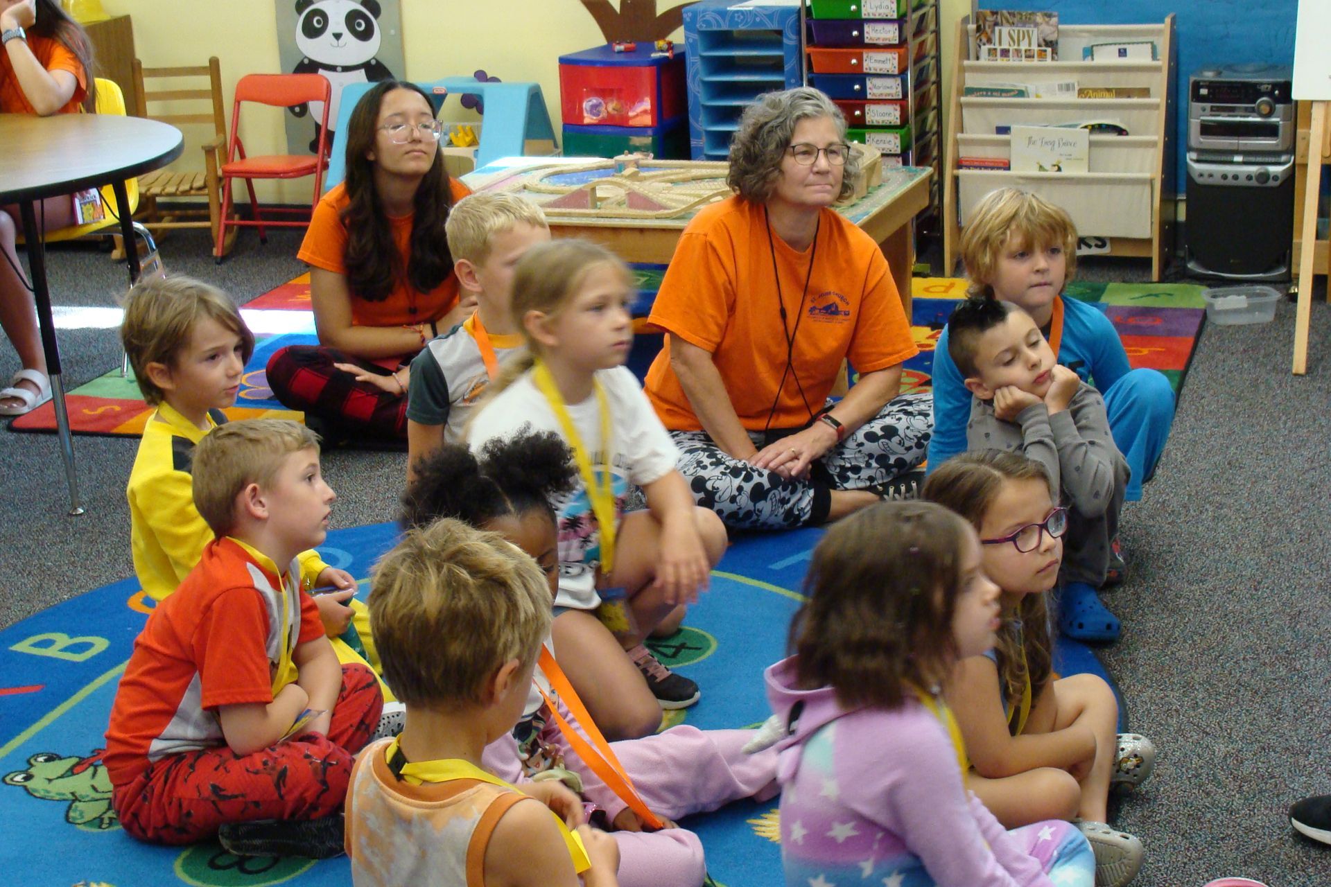 Children sitting on a classroom rug listening to a teacher during circle time