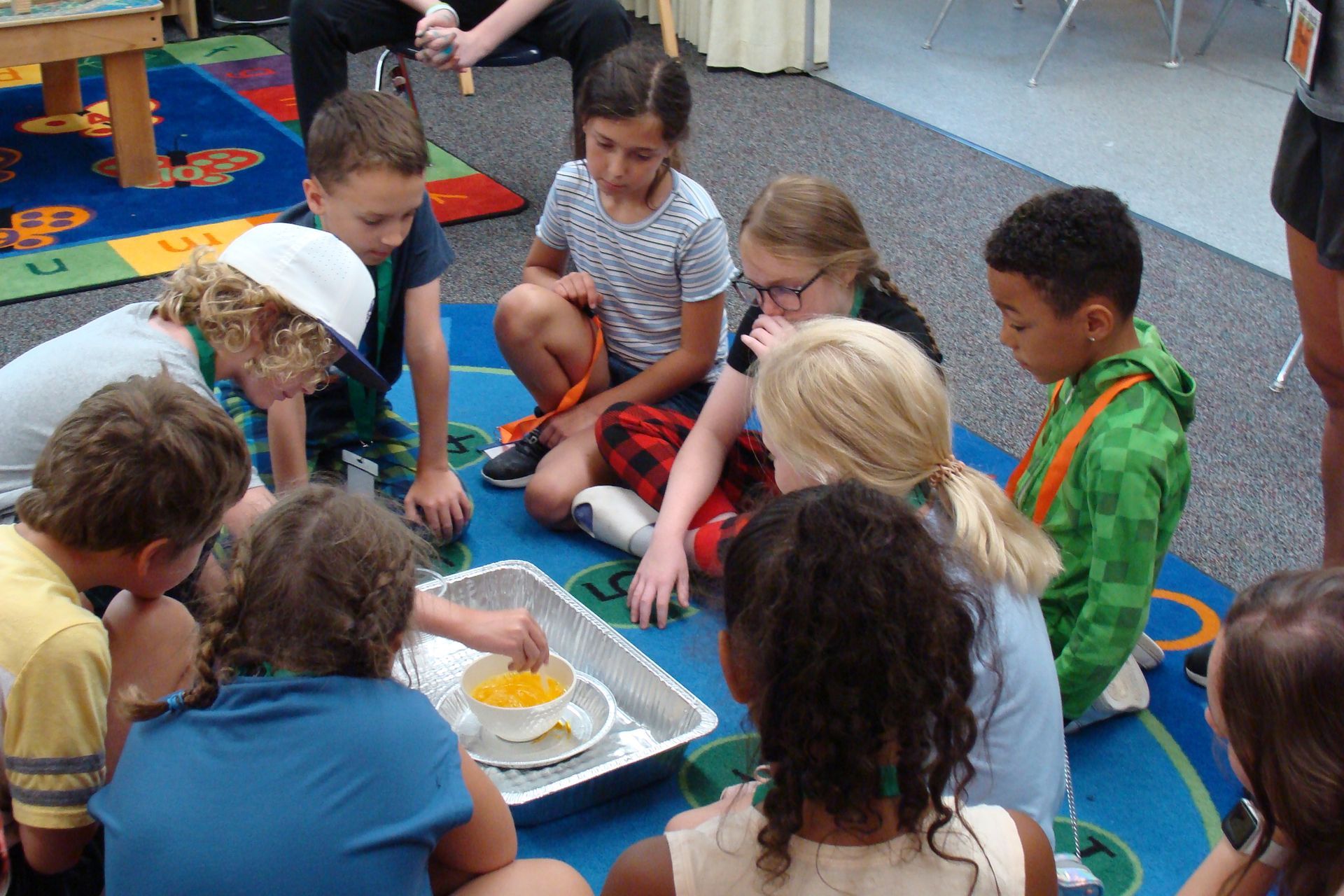 Children sit in a circle around a tray of food during a classroom activity.