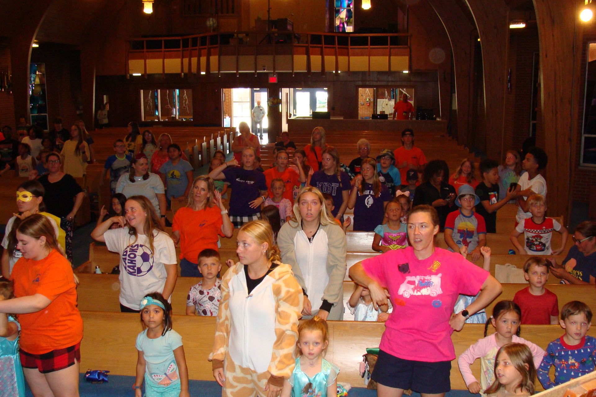 Crowded church hall with people of all ages standing and dancing at a gathering