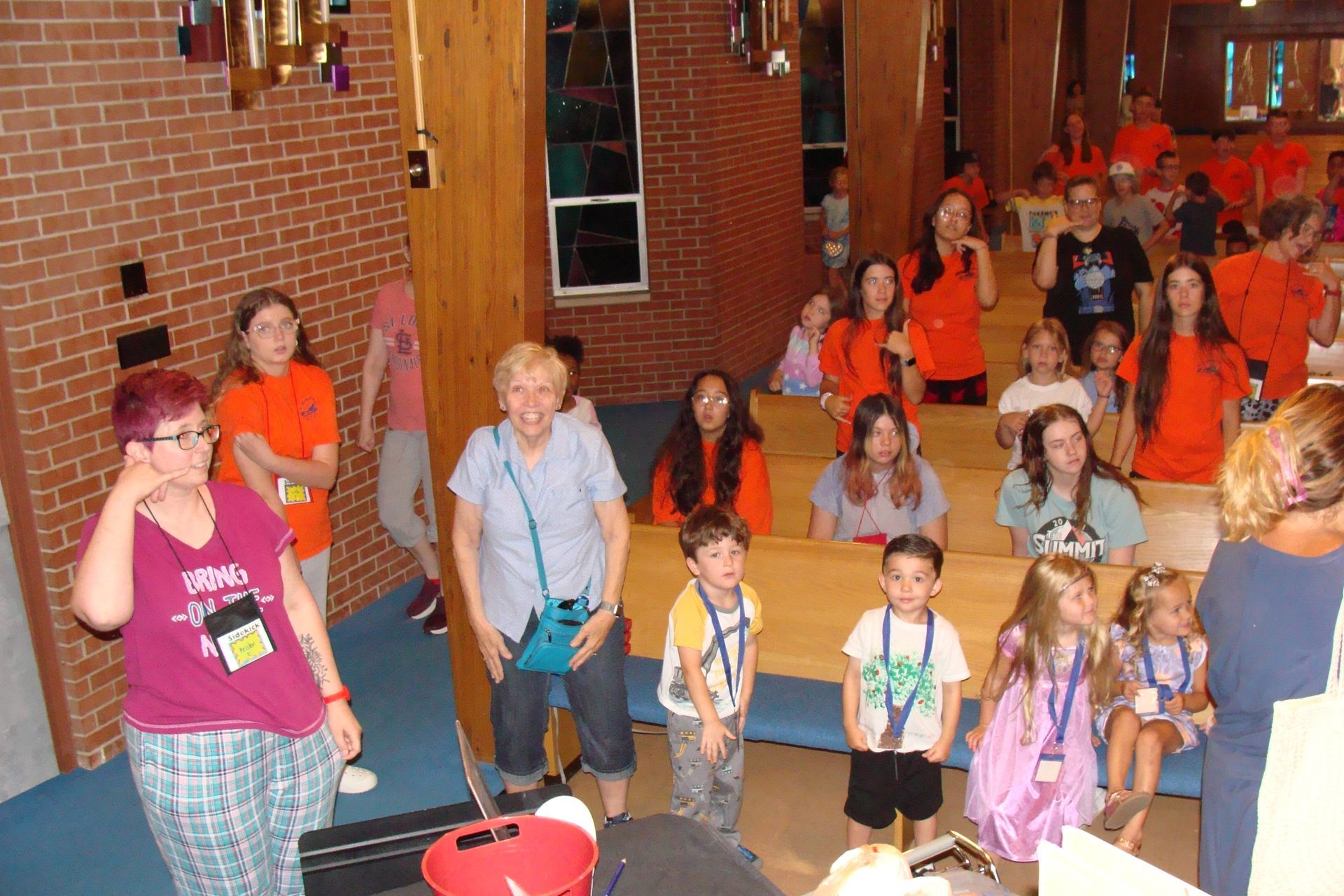 Group of people in orange shirts gathered in a brick hallway, posing and smiling