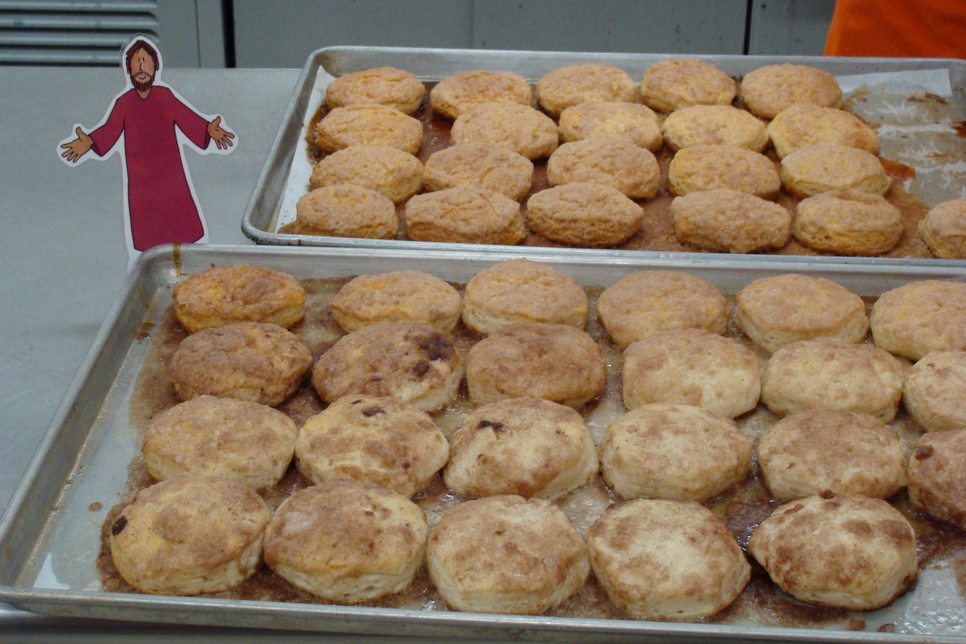 Two trays of baked pastries with a small red cardboard figure at the left edge