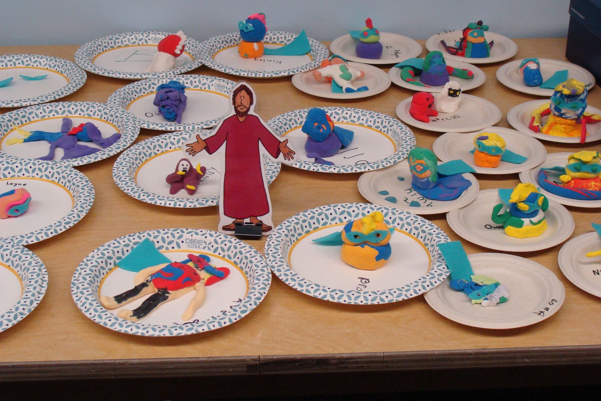Miniature figures displayed on decorated paper plates in a tabletop art arrangement