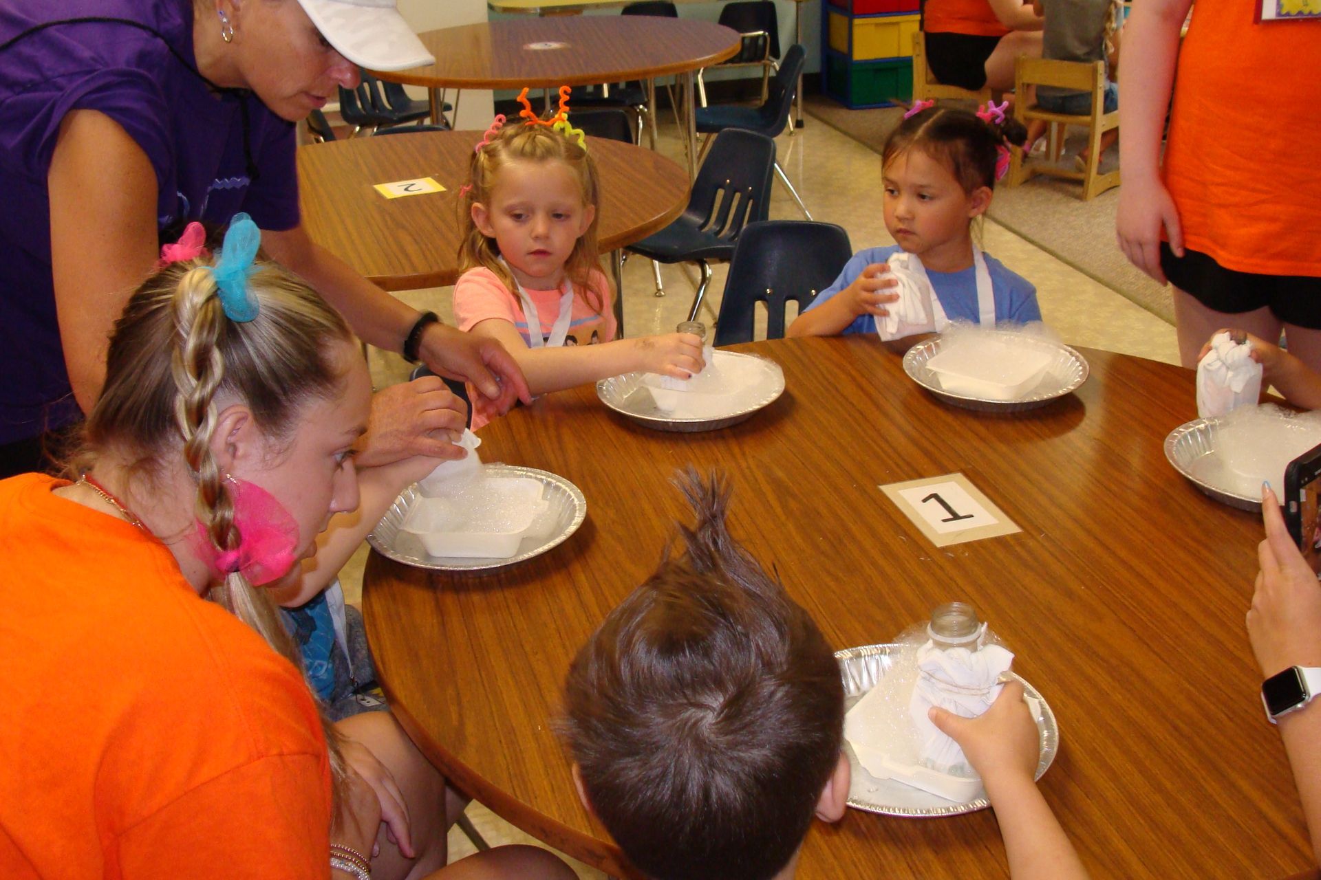 Children seated around a table eating from paper plates at a classroom snack activity