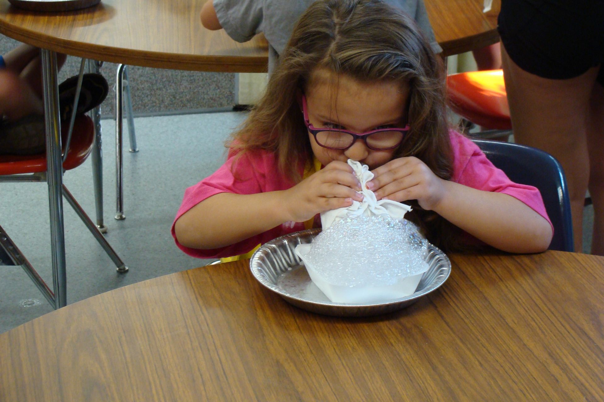 Child at a table, eating a large dessert with whipped cream in a cafeteria