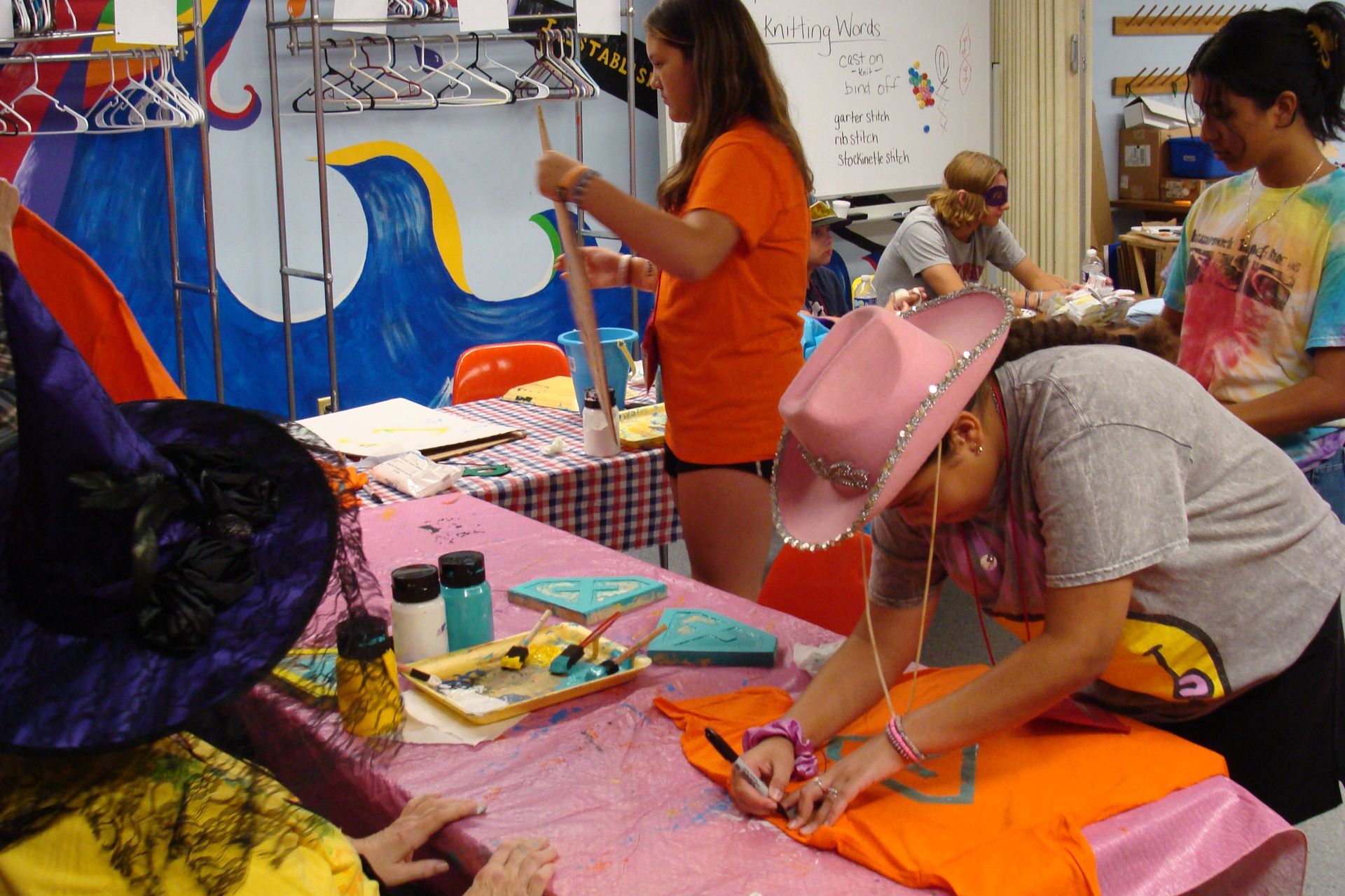 People crafting at a colorful table in an art classroom