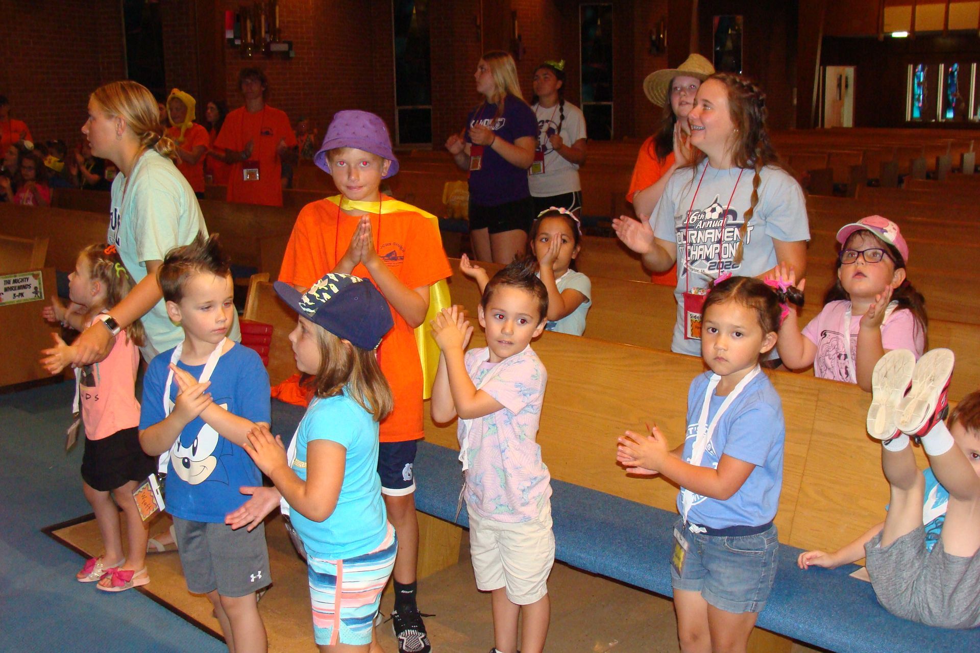 Children dancing in a room, holding colorful props during an indoor activity.