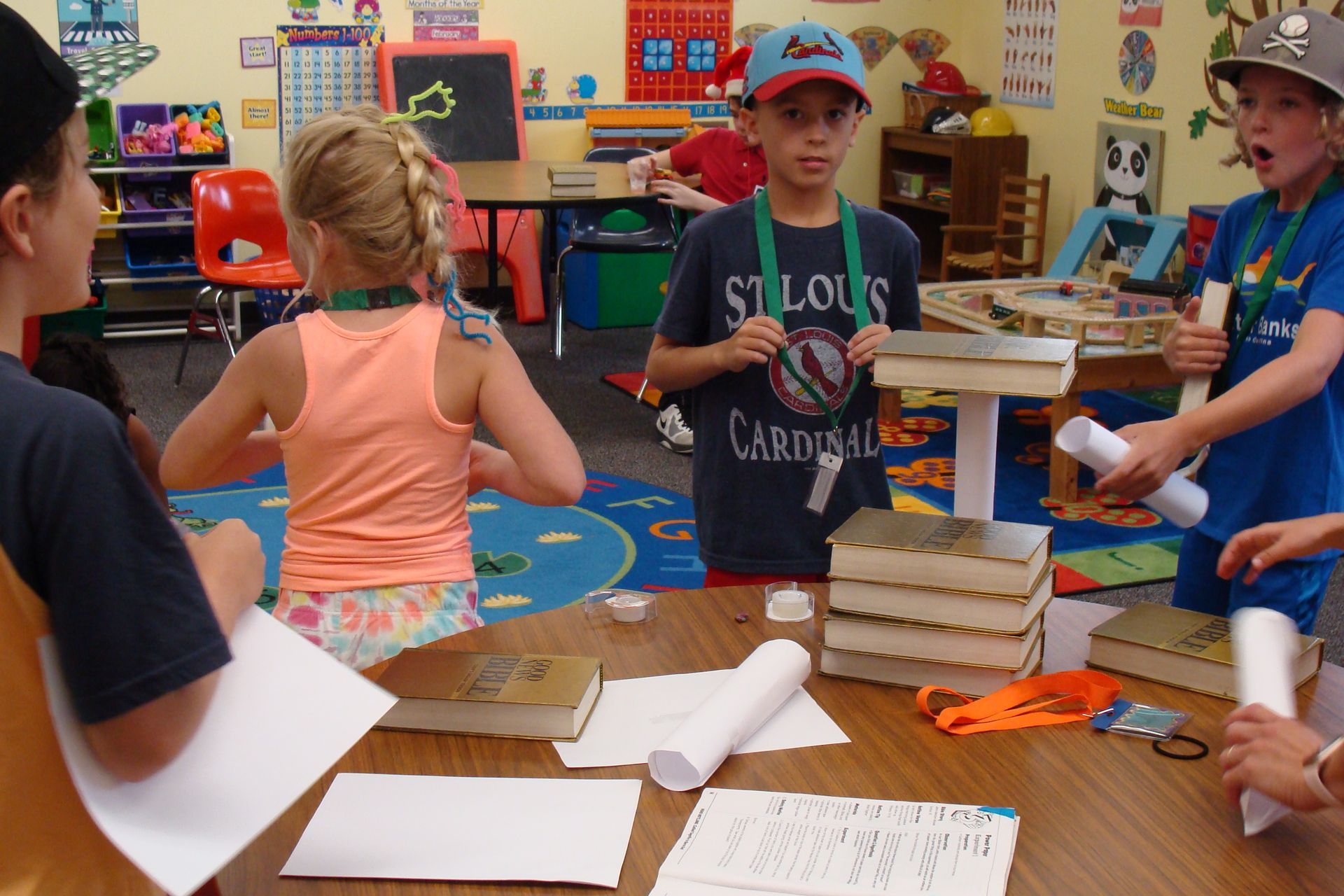 Children in a classroom building a tower of stacked books around a table