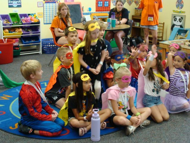 Children in costumes sitting on a classroom floor during a group activity