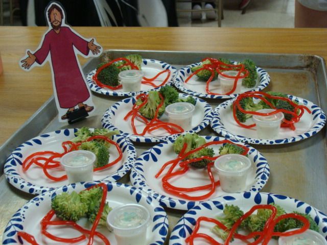 Paper plates with red and green ribbon on a table, with a small cutout figure at the back.