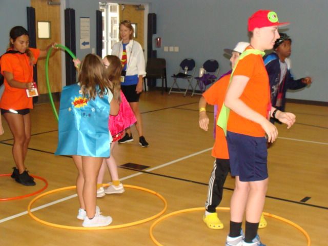 Children playing an indoor game with hula hoops in a gymnasium.