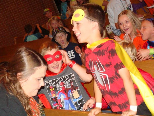 Children in superhero masks and costumes at a lively party scene