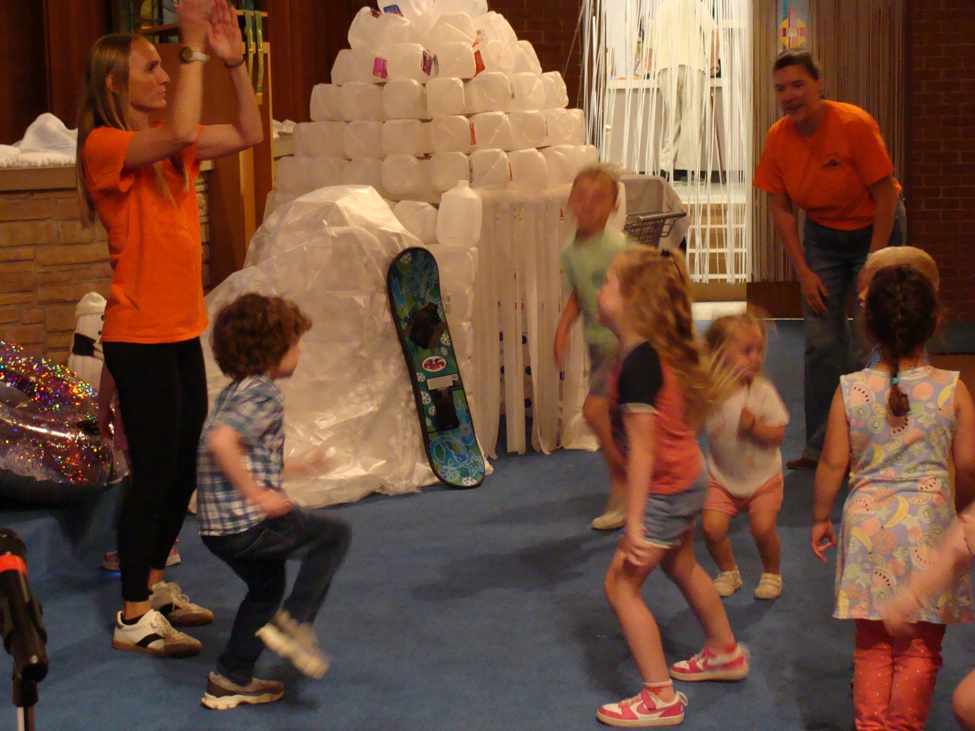Children play in front of a large white igloo-like display at an indoor event.