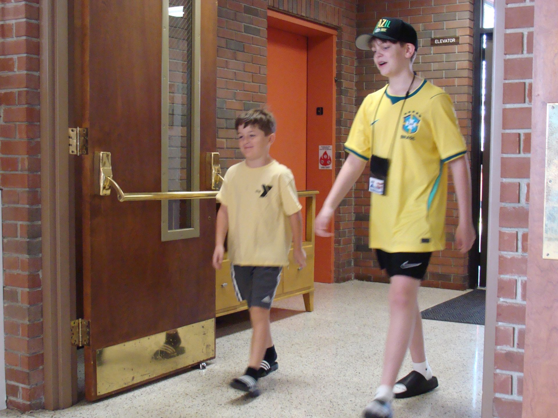 Two people walking through a brick hallway near an open wooden door