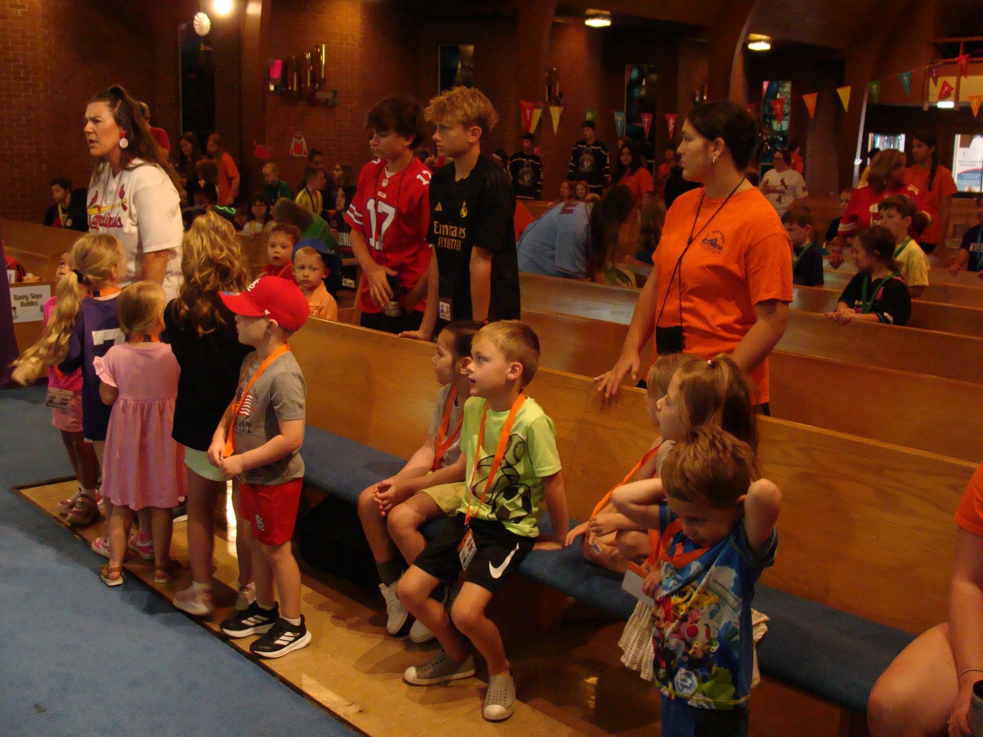 Children lined up in a church aisle, singing and wearing colorful clothes during a service