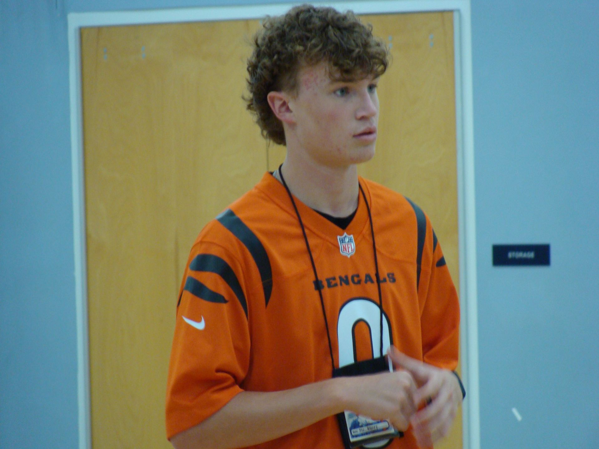 Orange-clad football player in a hallway, holding a ball and looking to the side