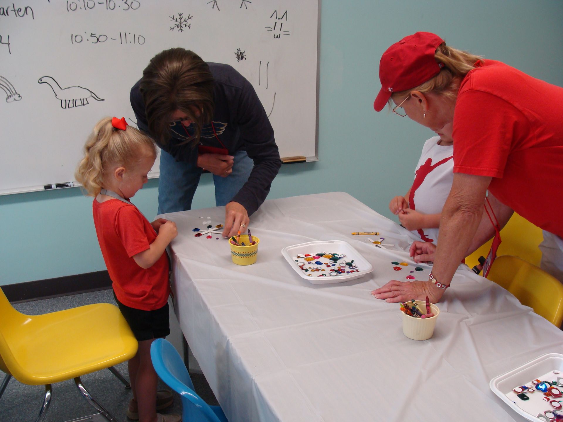 People painting at a table during a craft activity with adult supervision