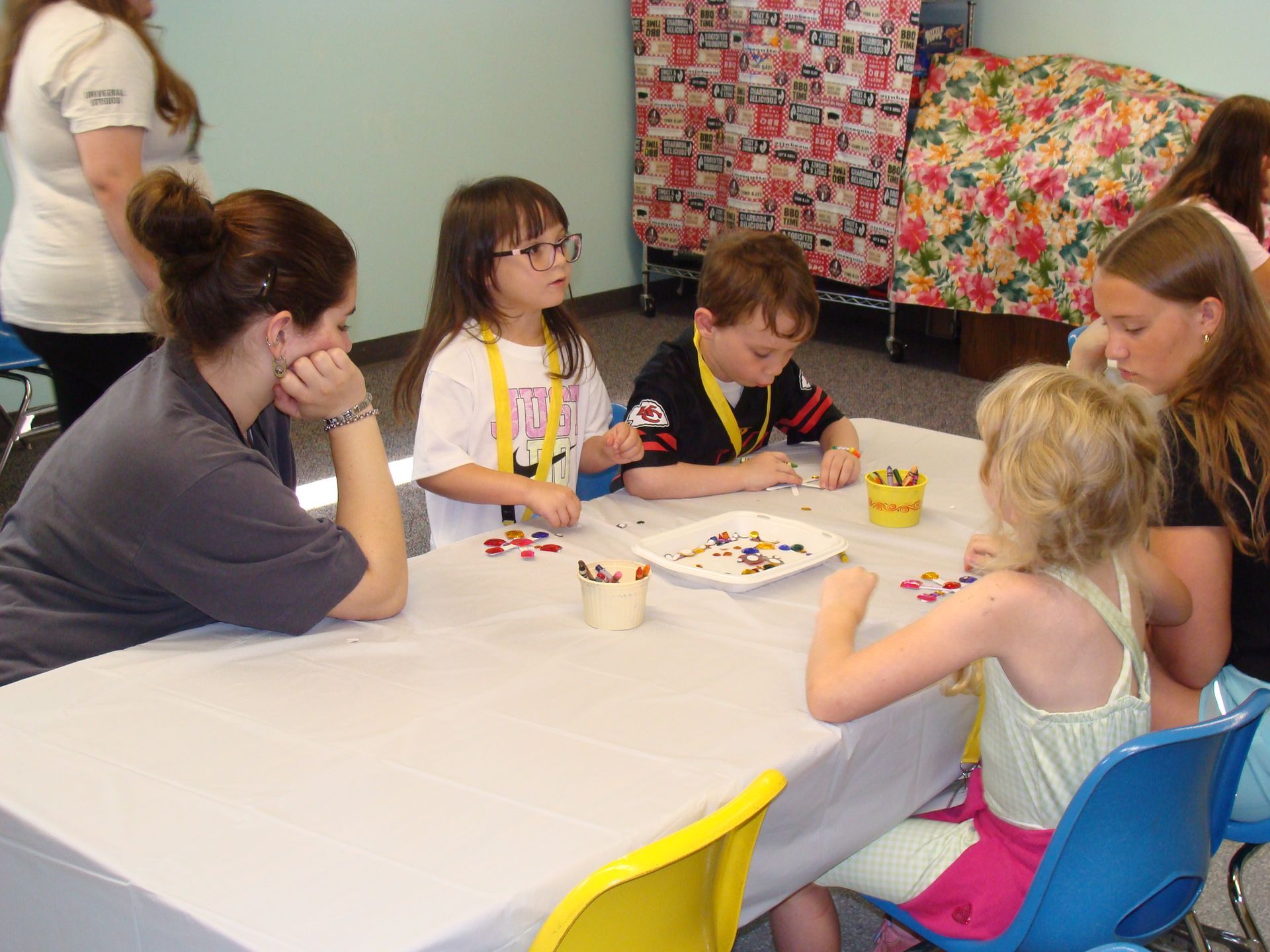 Children sit around a table playing a board game in a colorful room.