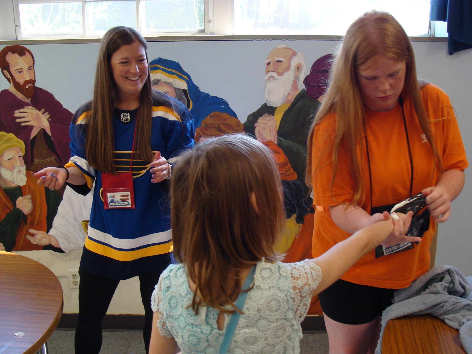 People holding cameras in a bright room with a mural in the background