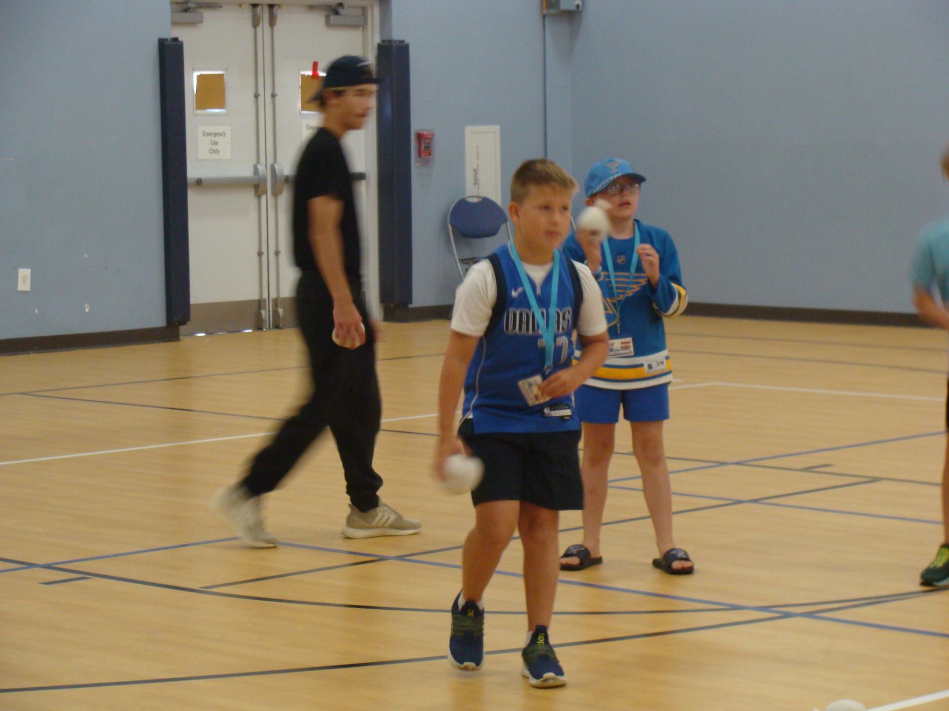 Children in blue sports uniforms standing on an indoor gym court during a game