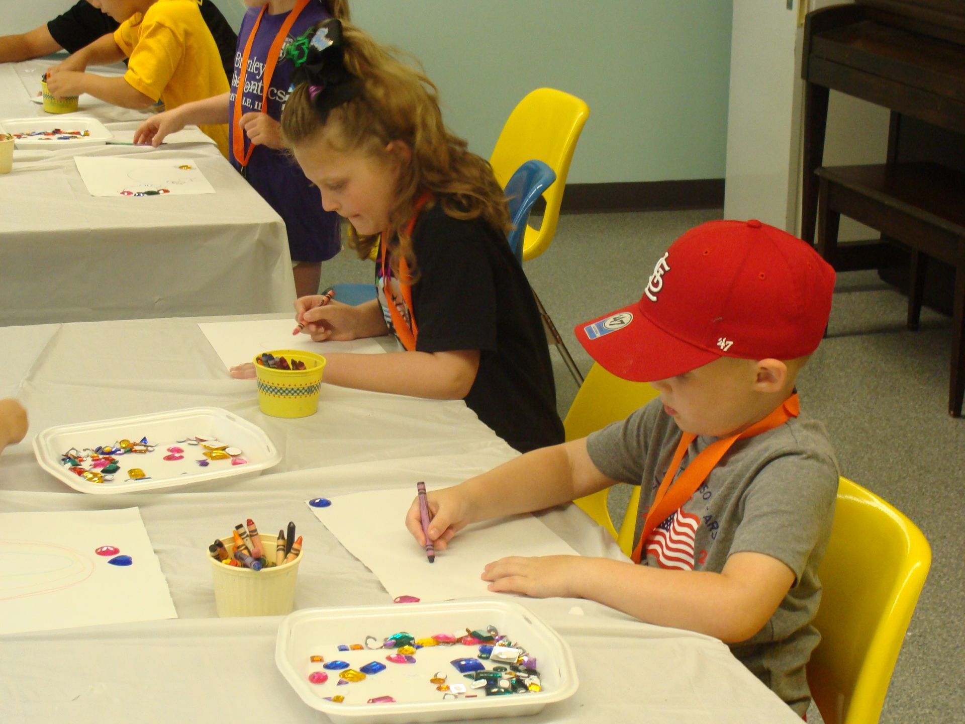Children sitting at tables, coloring with crayons in a classroom activity.