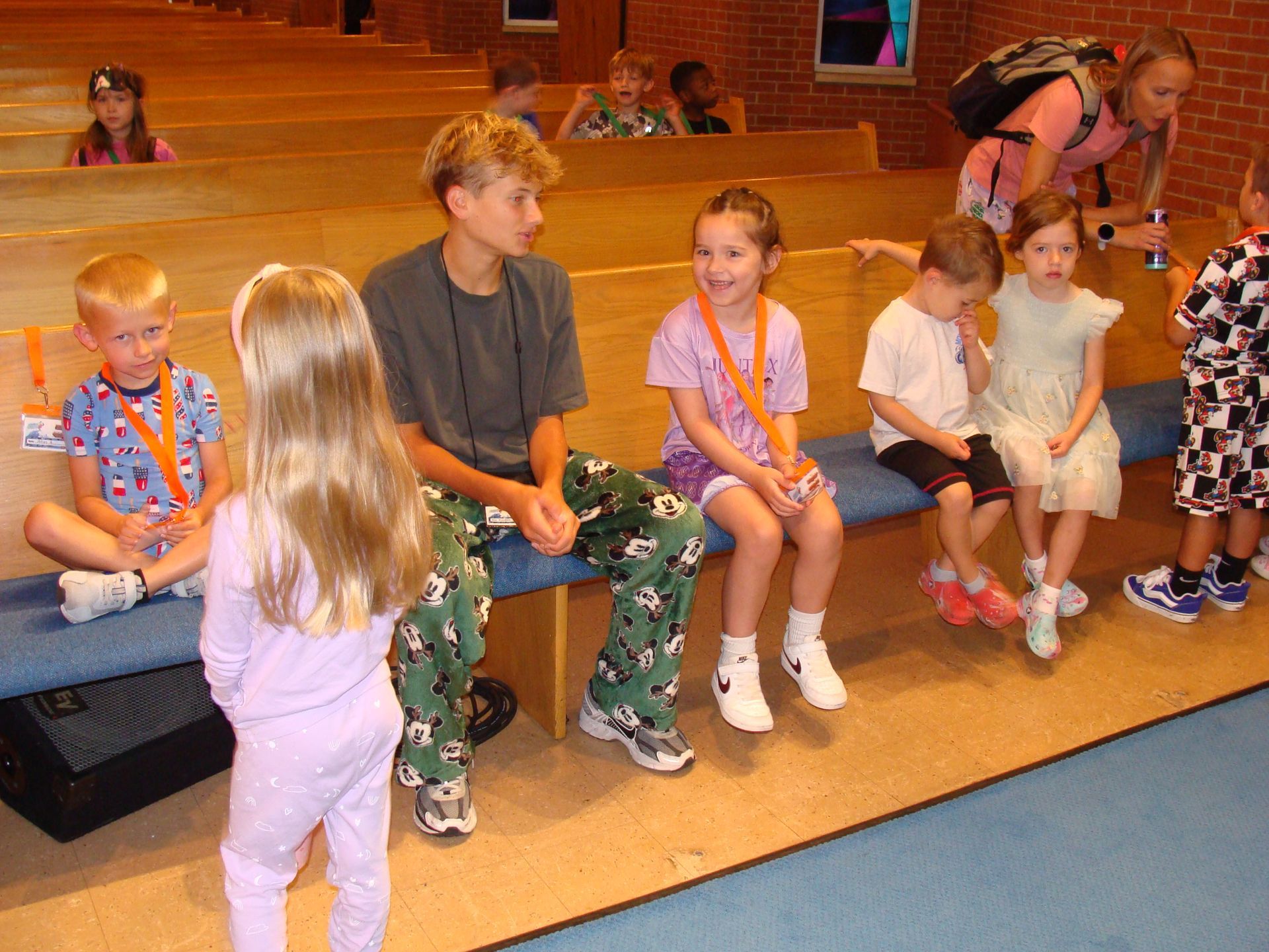 Children sitting on church pews, one boy and girl chatting, in a bright indoor hall