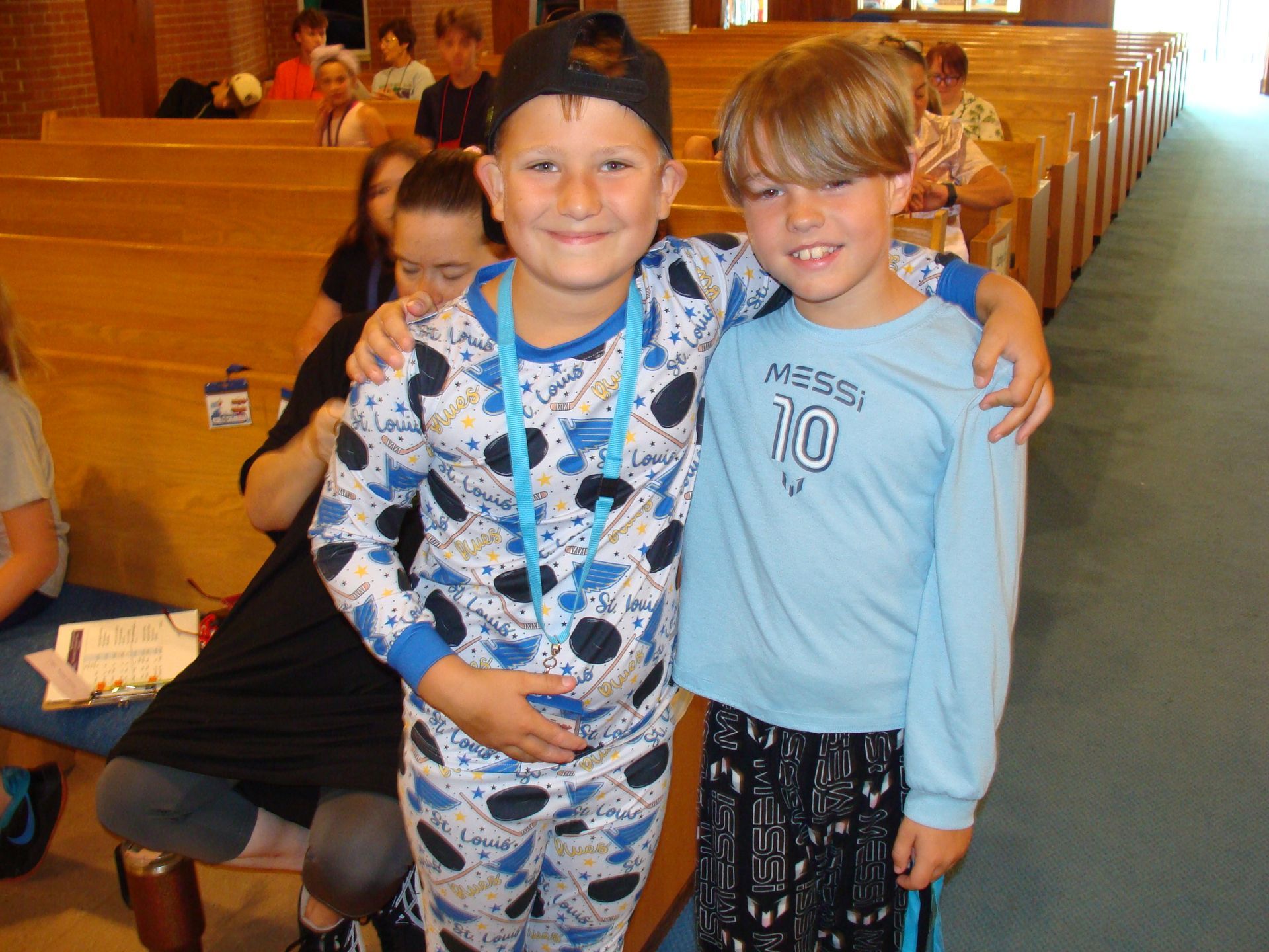 Two smiling children standing together in a church pews