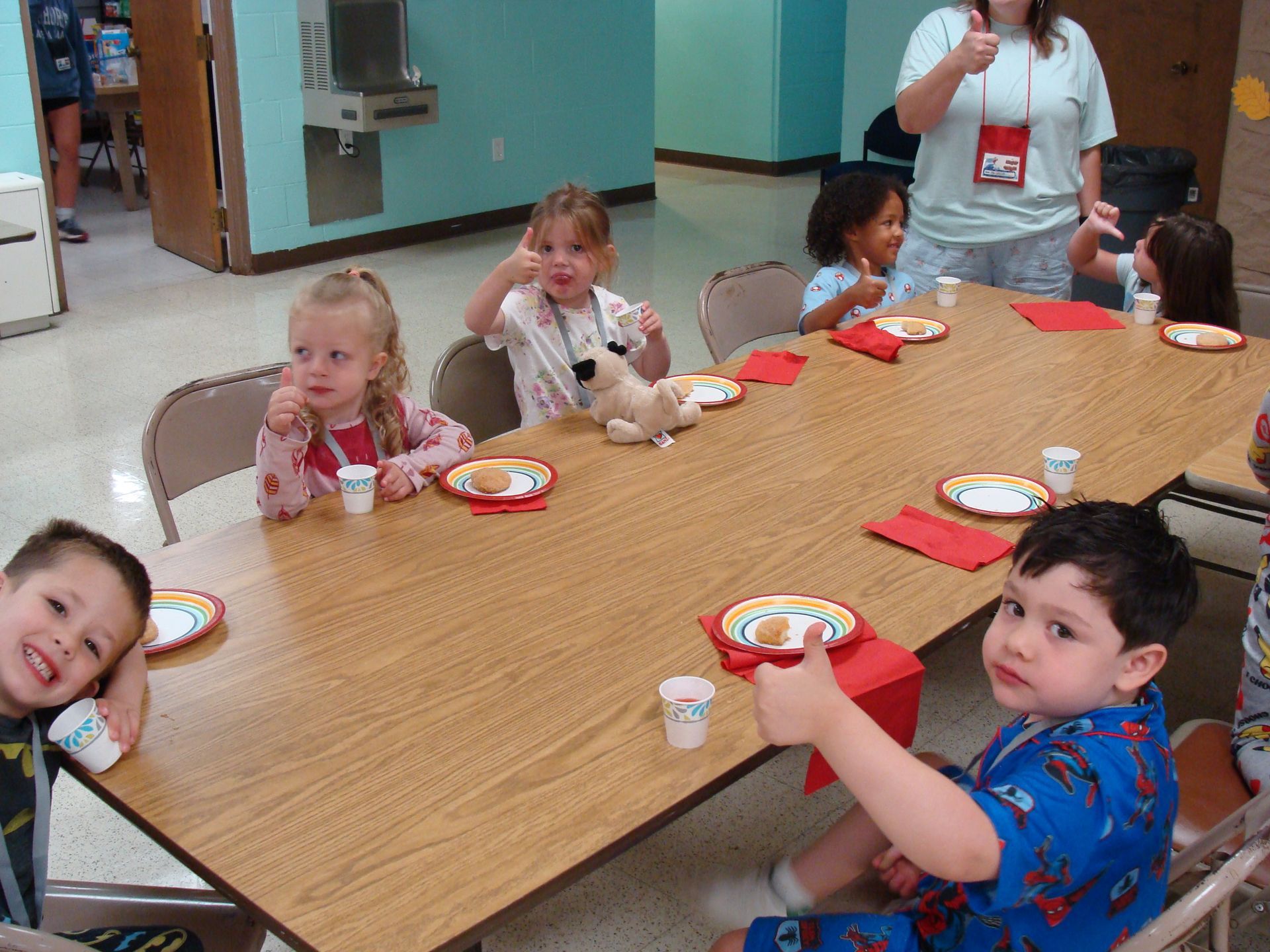 Children seated around a table eating snacks in a classroom or cafeteria setting