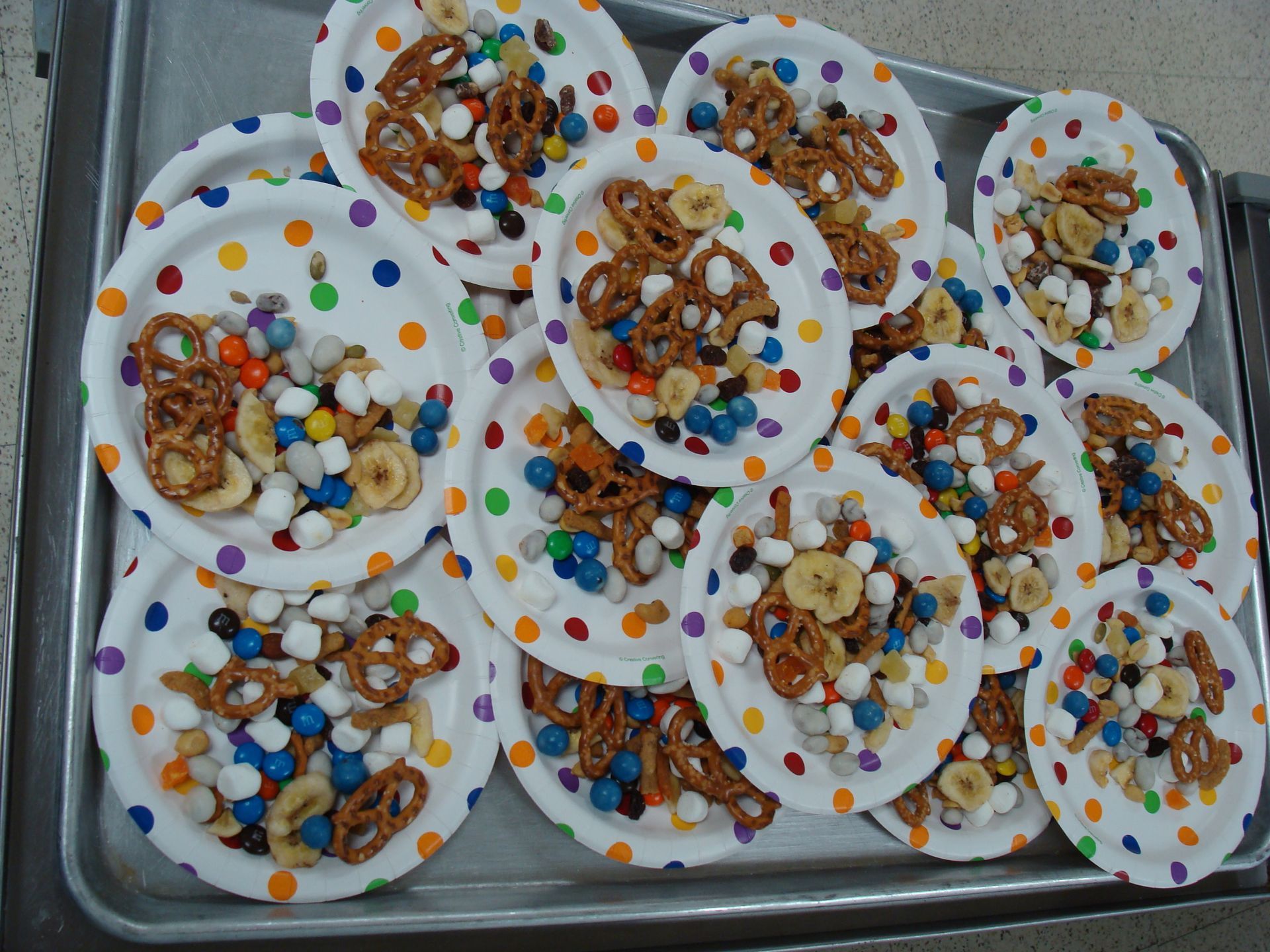 Assorted small desserts topped with colorful candies on a tray, arranged in white cups.
