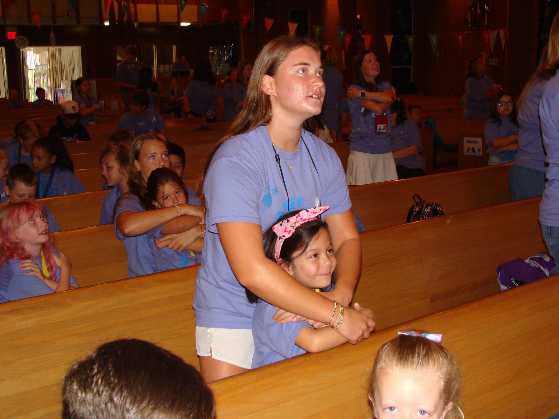 Woman hugging a child in a church pew, with other children seated nearby.