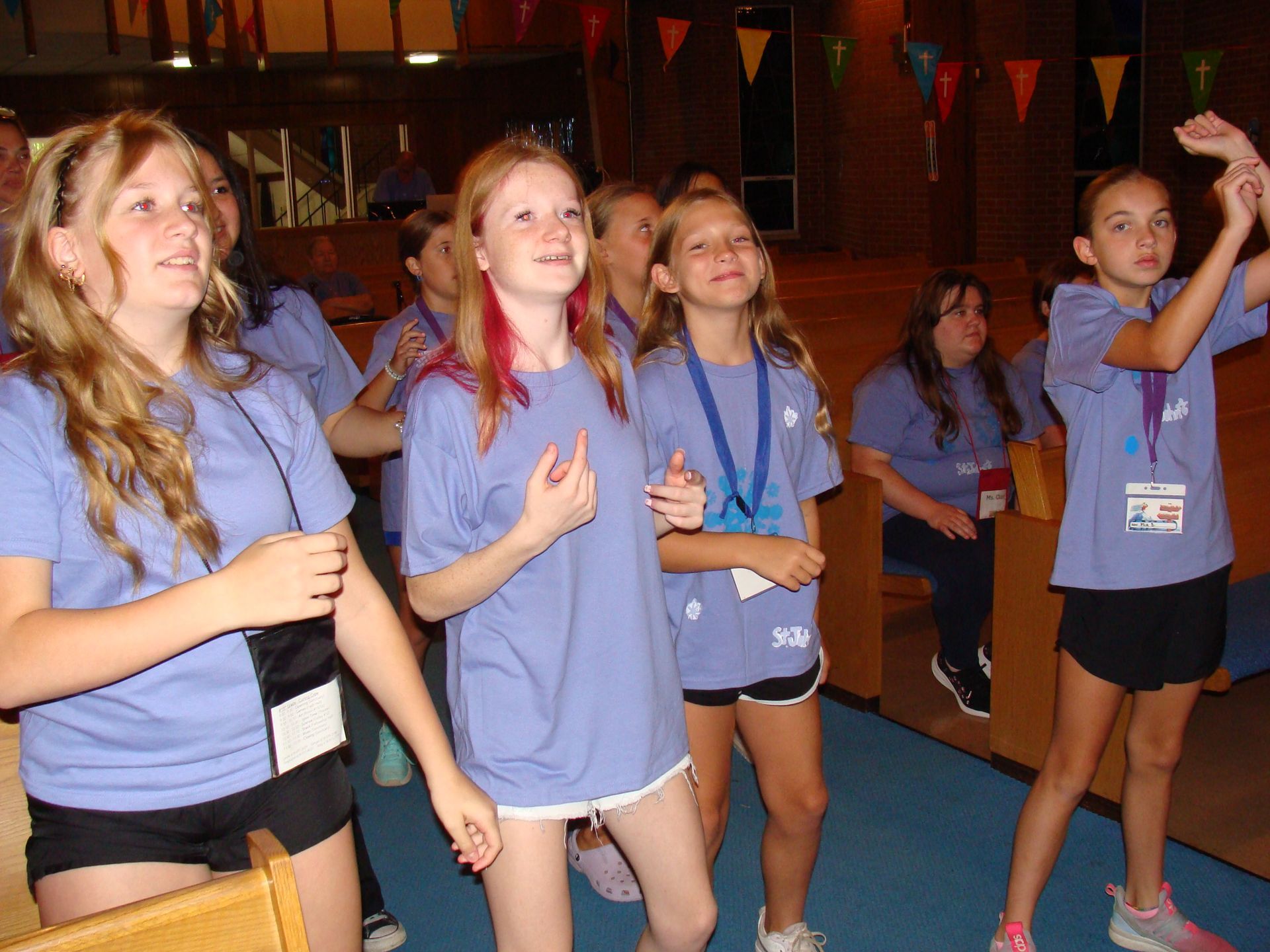 Group of children in blue shirts dancing indoors at an event
