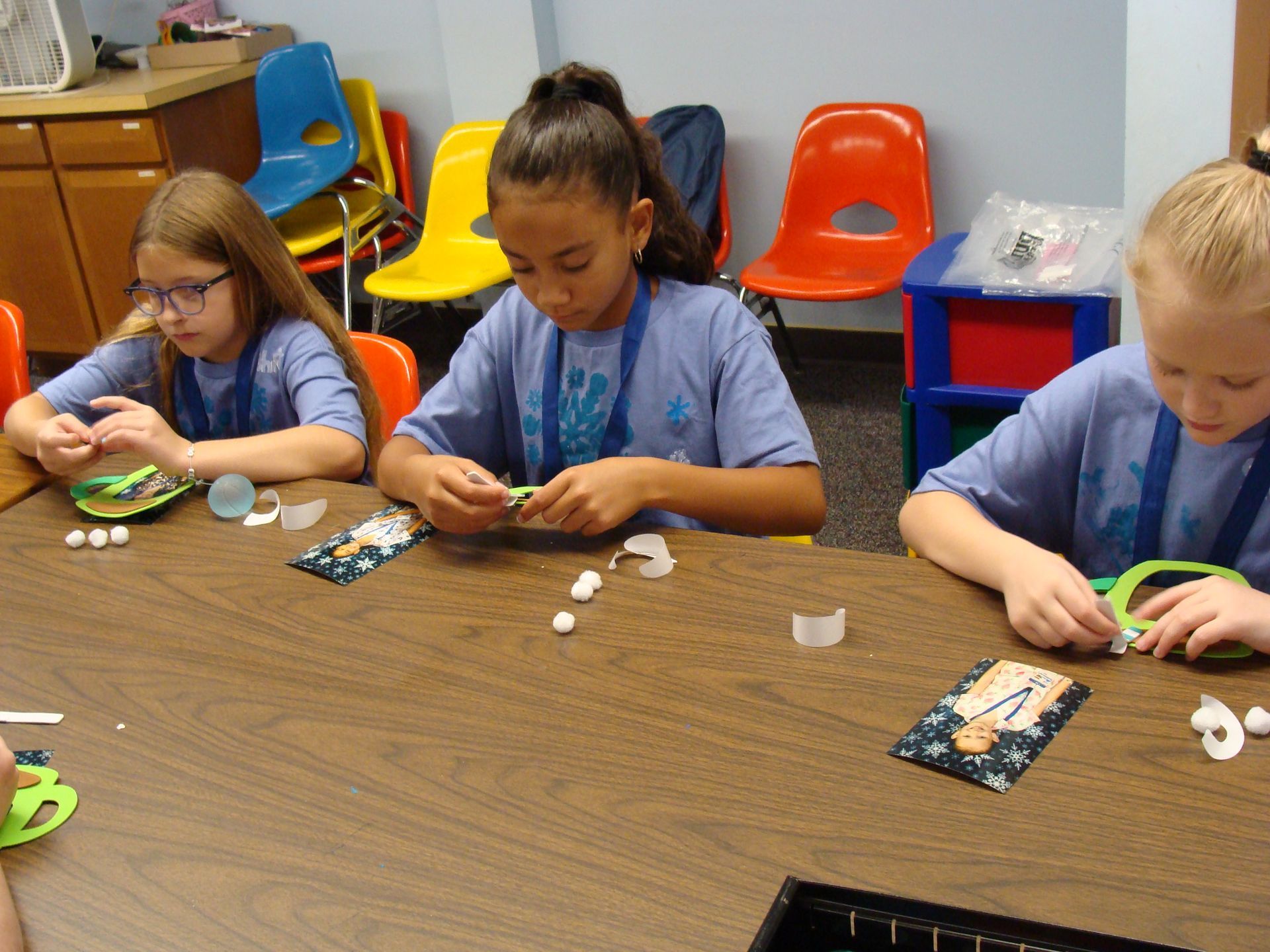 Children playing a tabletop sorting game in a classroom, focused on small objects and cards.