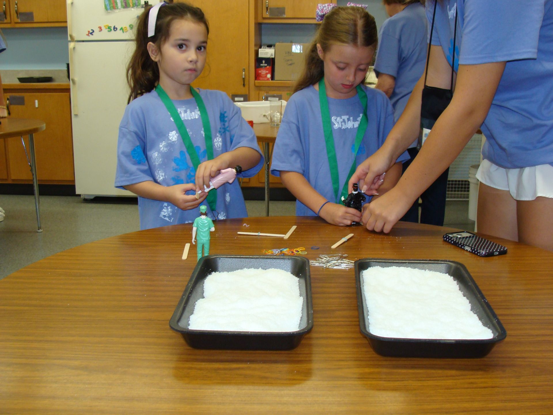 Two children at a table making science experiments with trays of white foam and tools