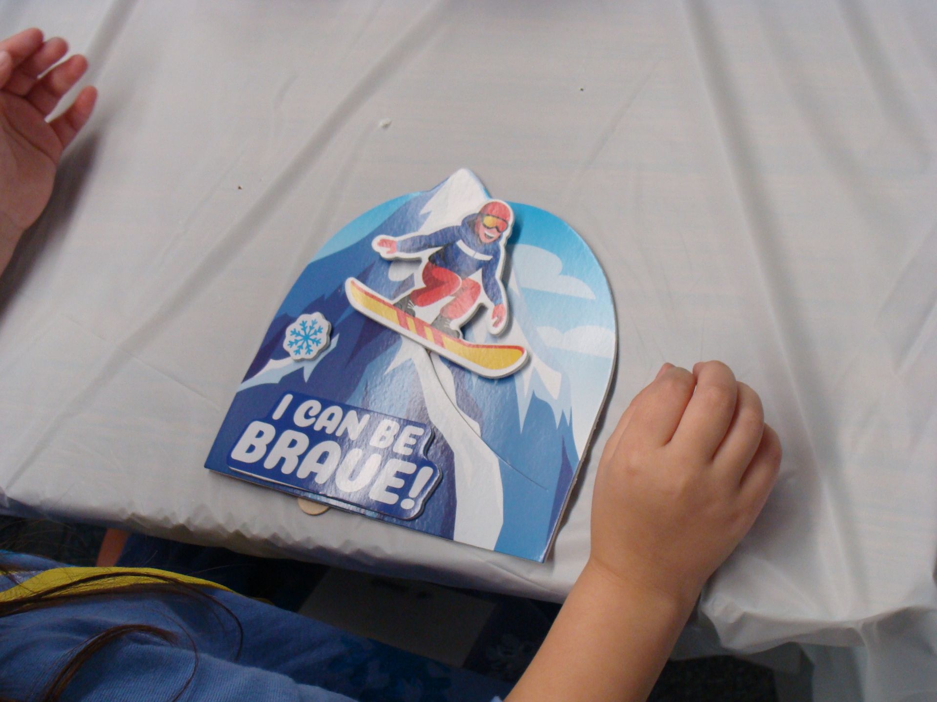 Child’s hands beside a blue “I can be a BRAVE!” book on a table