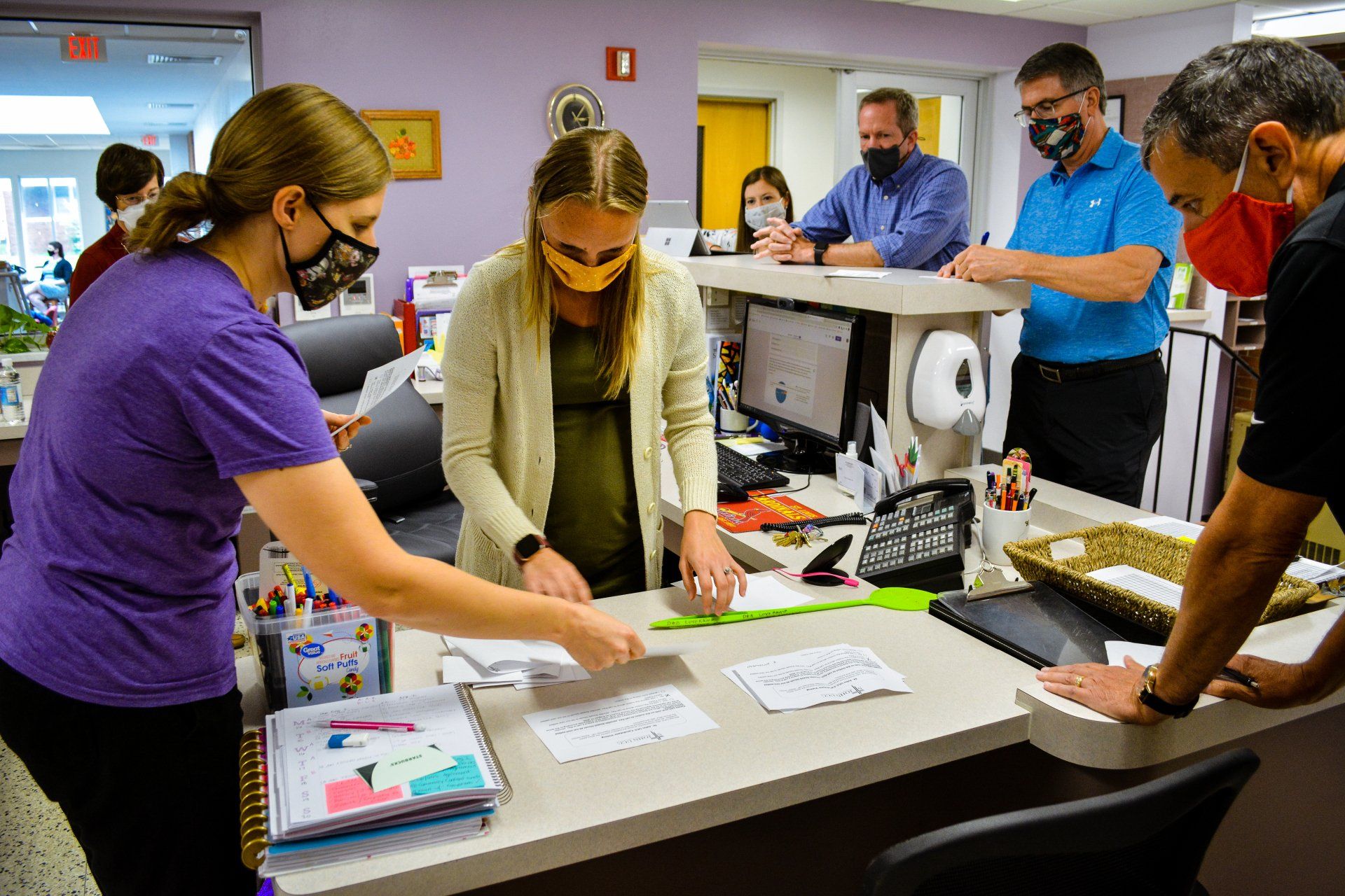 People collaborating around a table in an office, reviewing documents and a laptop.
