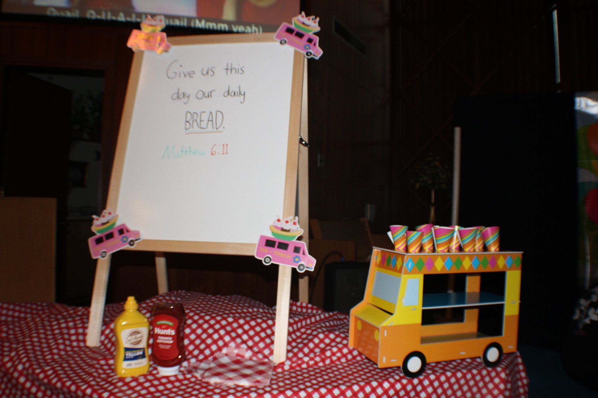 Decorated easel with “Read” sign beside a yellow school bus centerpiece and toy bottles on a red tablecloth