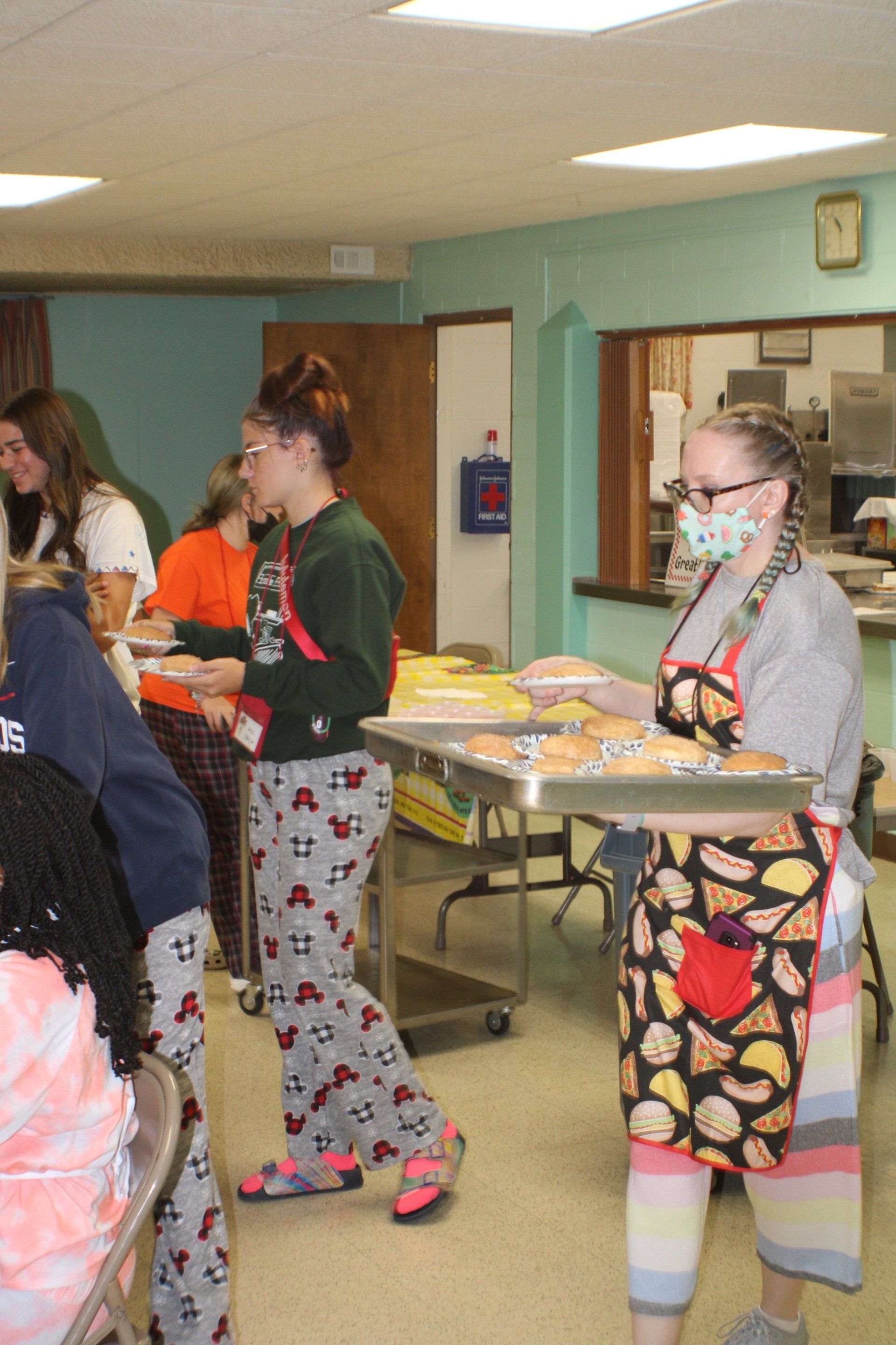 People in a room carrying trays of food at a casual gathering