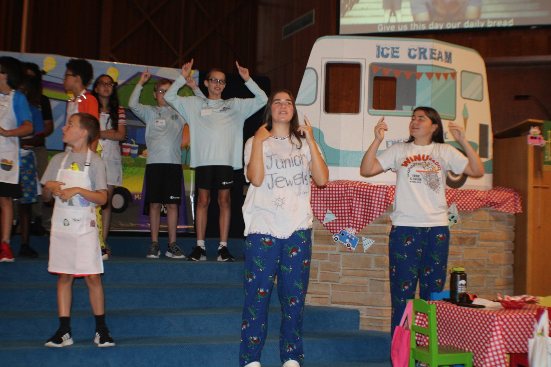Children performing on a stage near an ice cream stand display