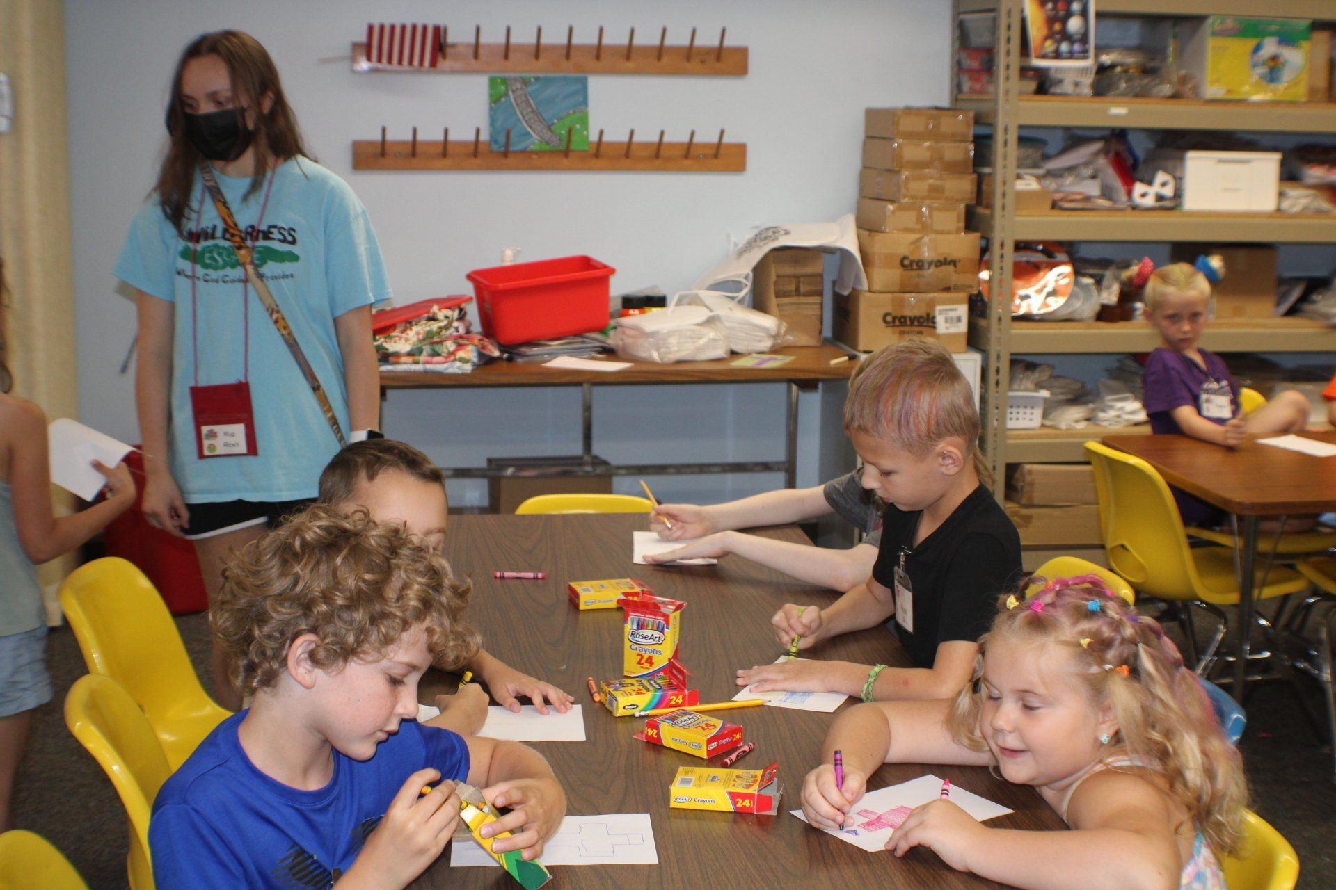 Children and a teacher sit at a table eating snacks in a classroom