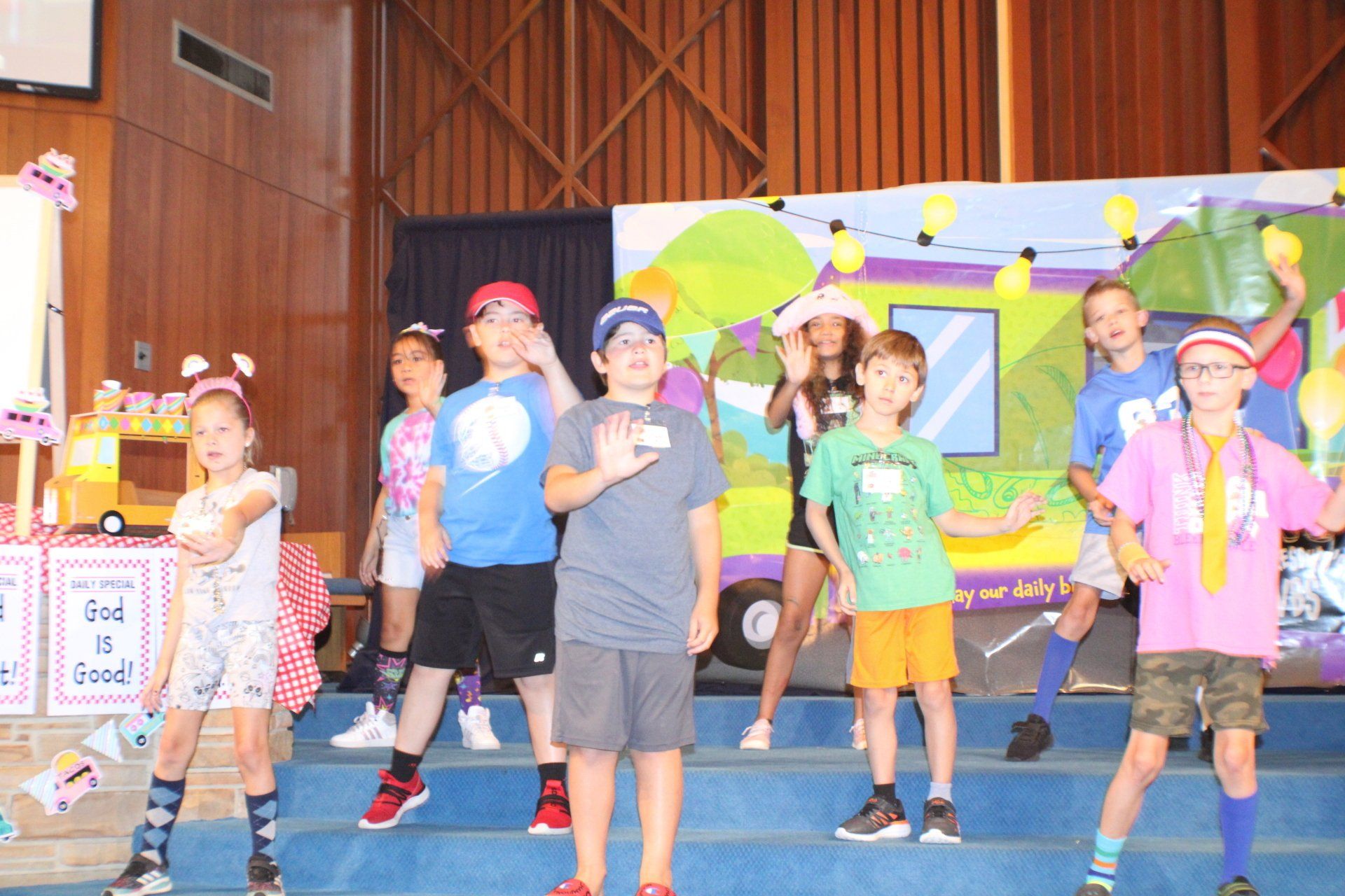Children dancing on a stage in colorful costumes during a school performance
