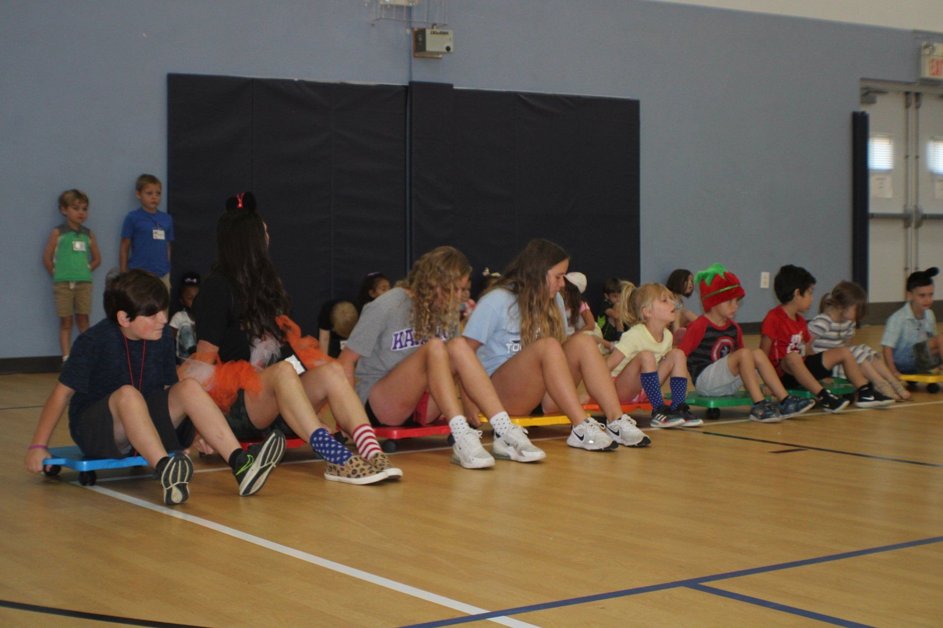 Children sitting in a line on the gym floor, preparing for a school activity