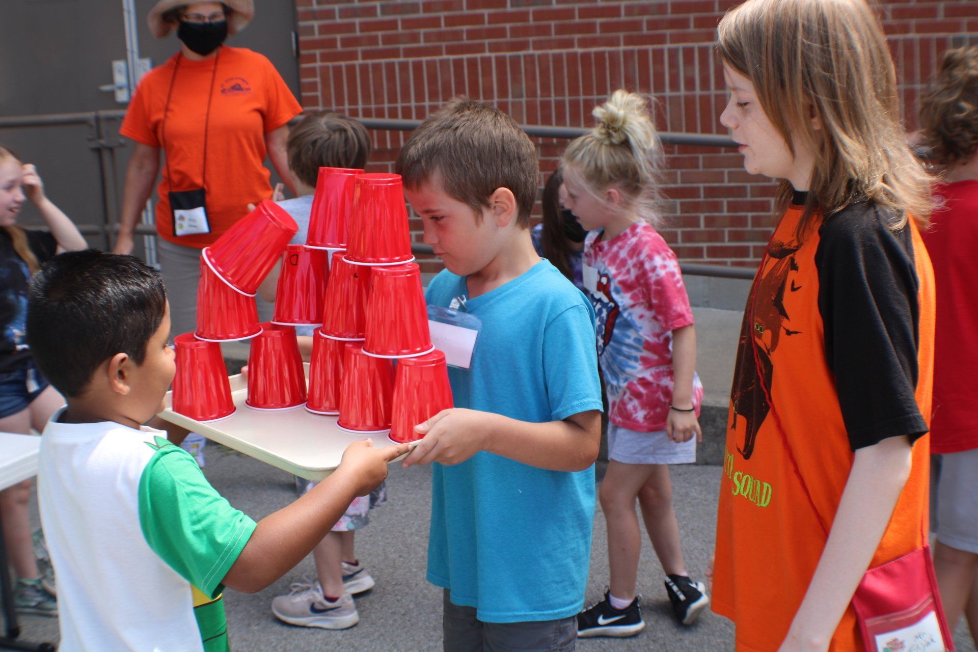 Children stacking red cups outdoors in a schoolyard game