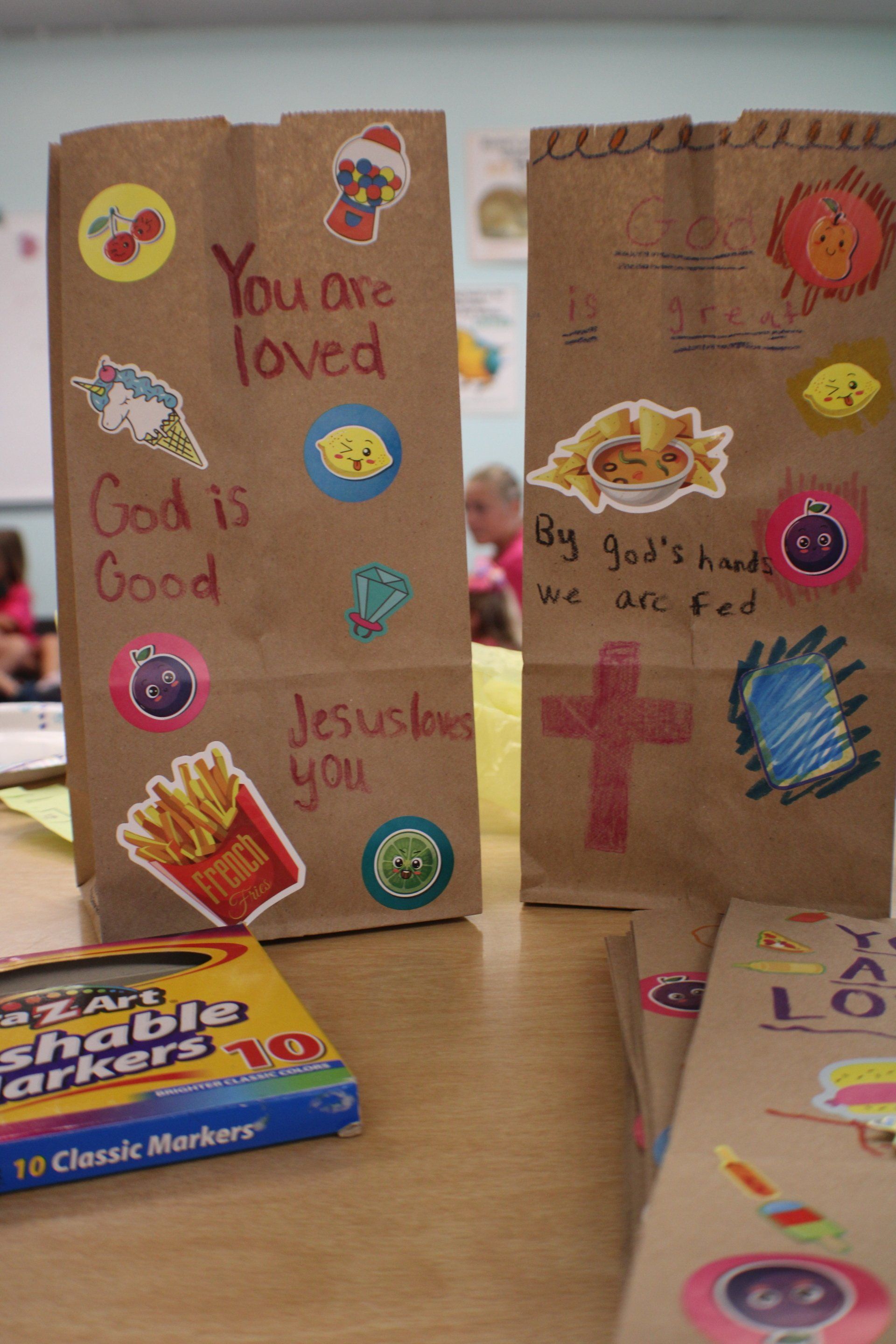 Decorated paper bags with colorful stickers and handwritten messages on a table