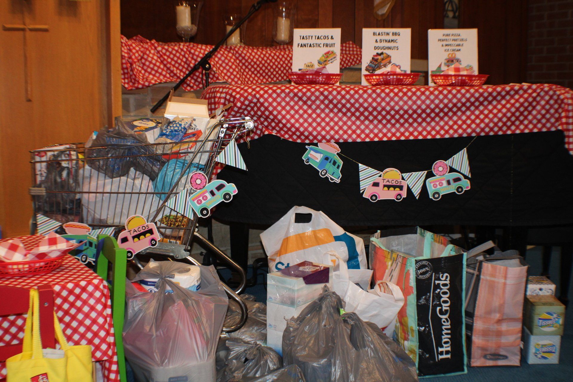 Gift table with red checkered cloth, bags, baskets, and colorful bunting decorations.