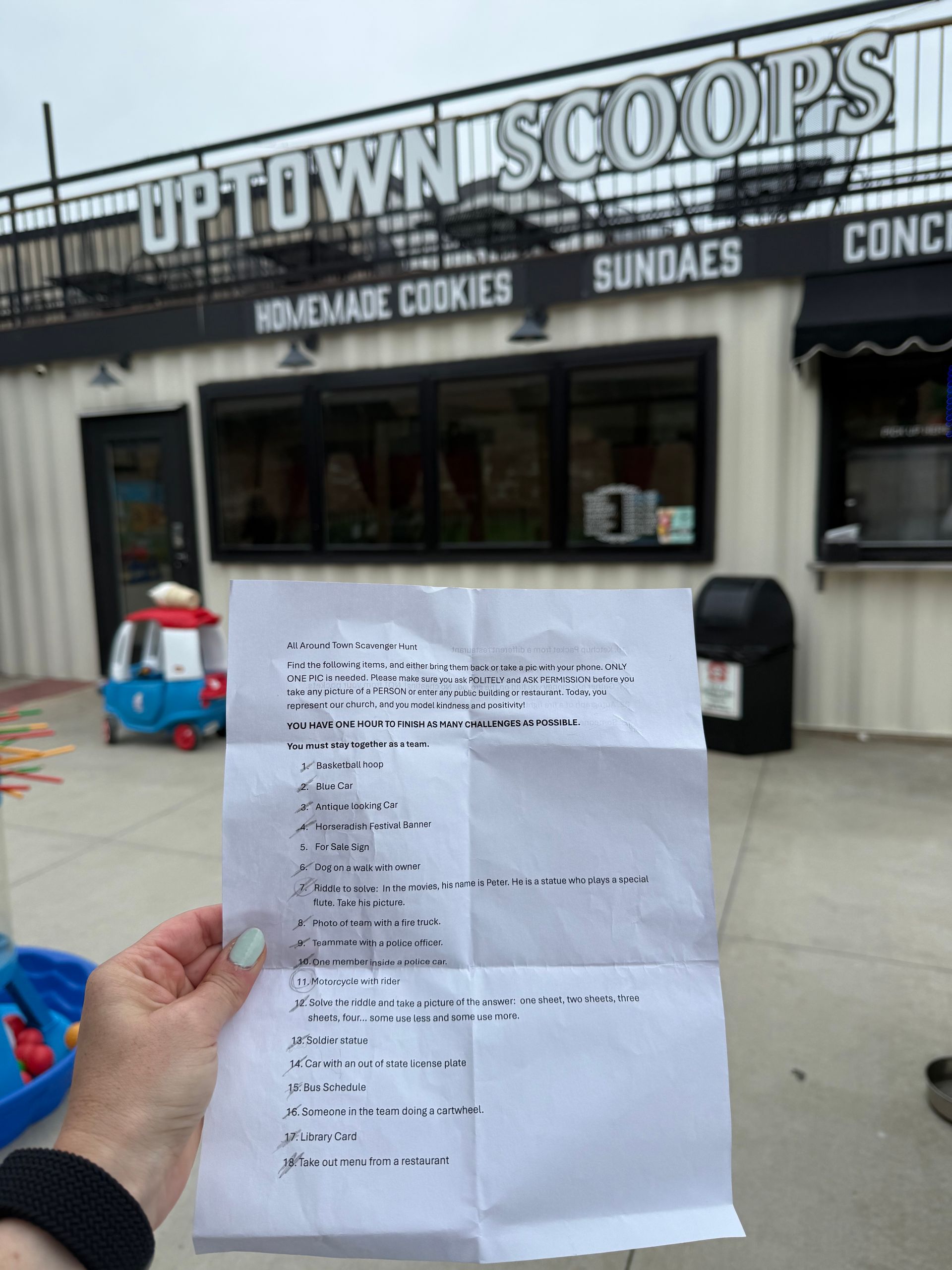 Hand holding a printed receipt in front of Uptown Scoops ice cream shop storefront