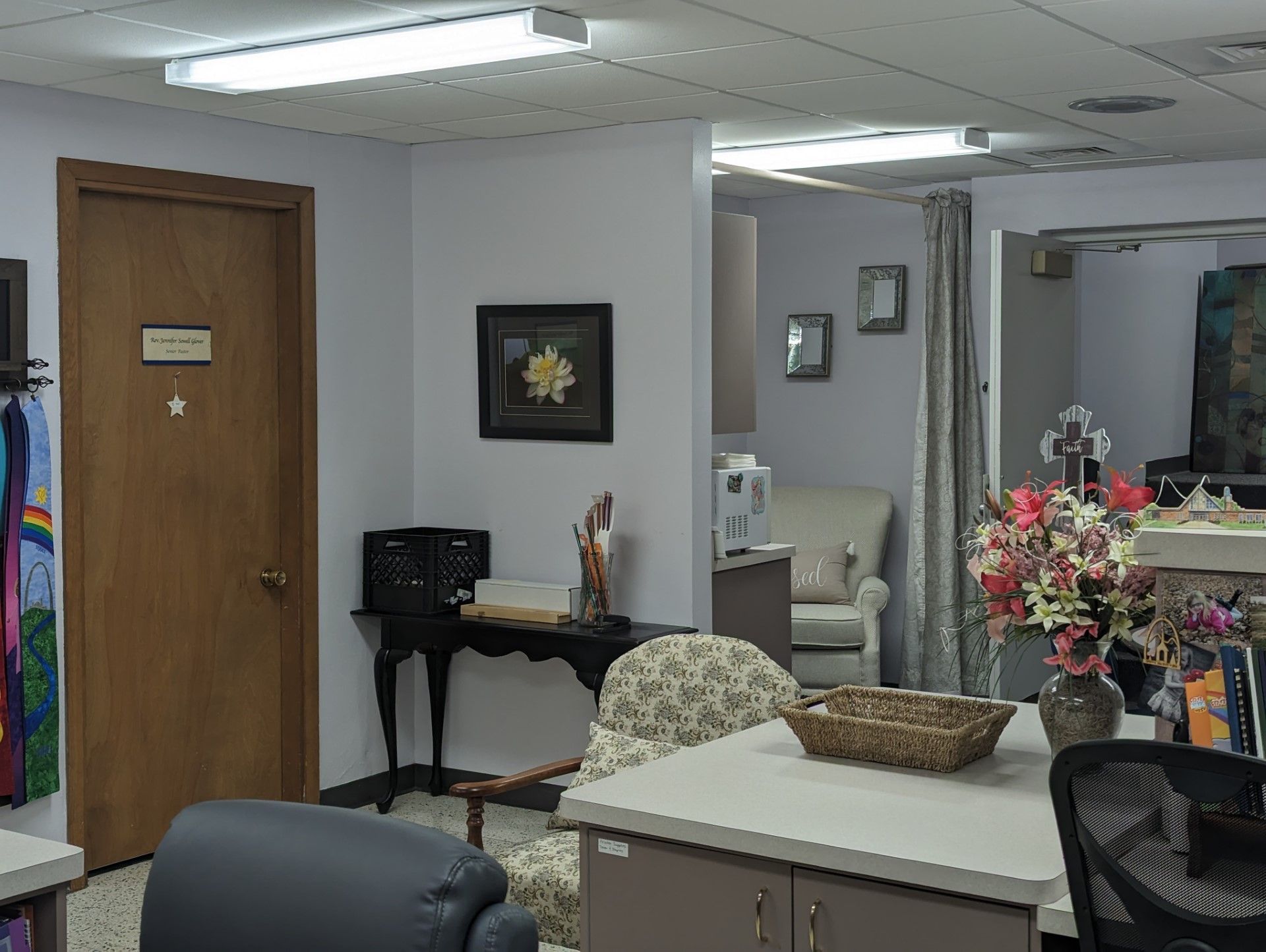 Office lobby with desk, chairs, wooden door, and flower arrangements