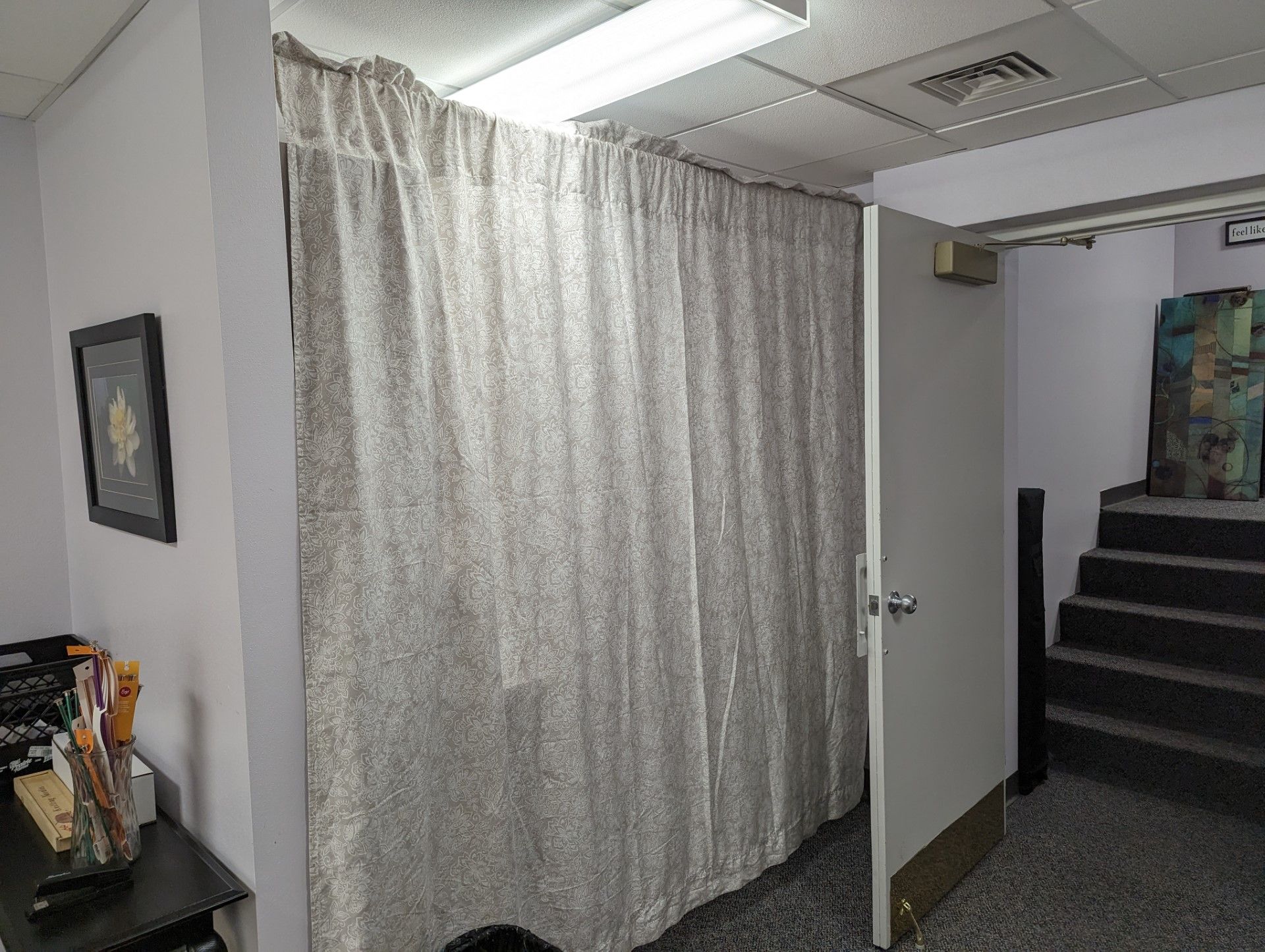 Curtained hallway beside stairs in a plain office interior with fluorescent lighting